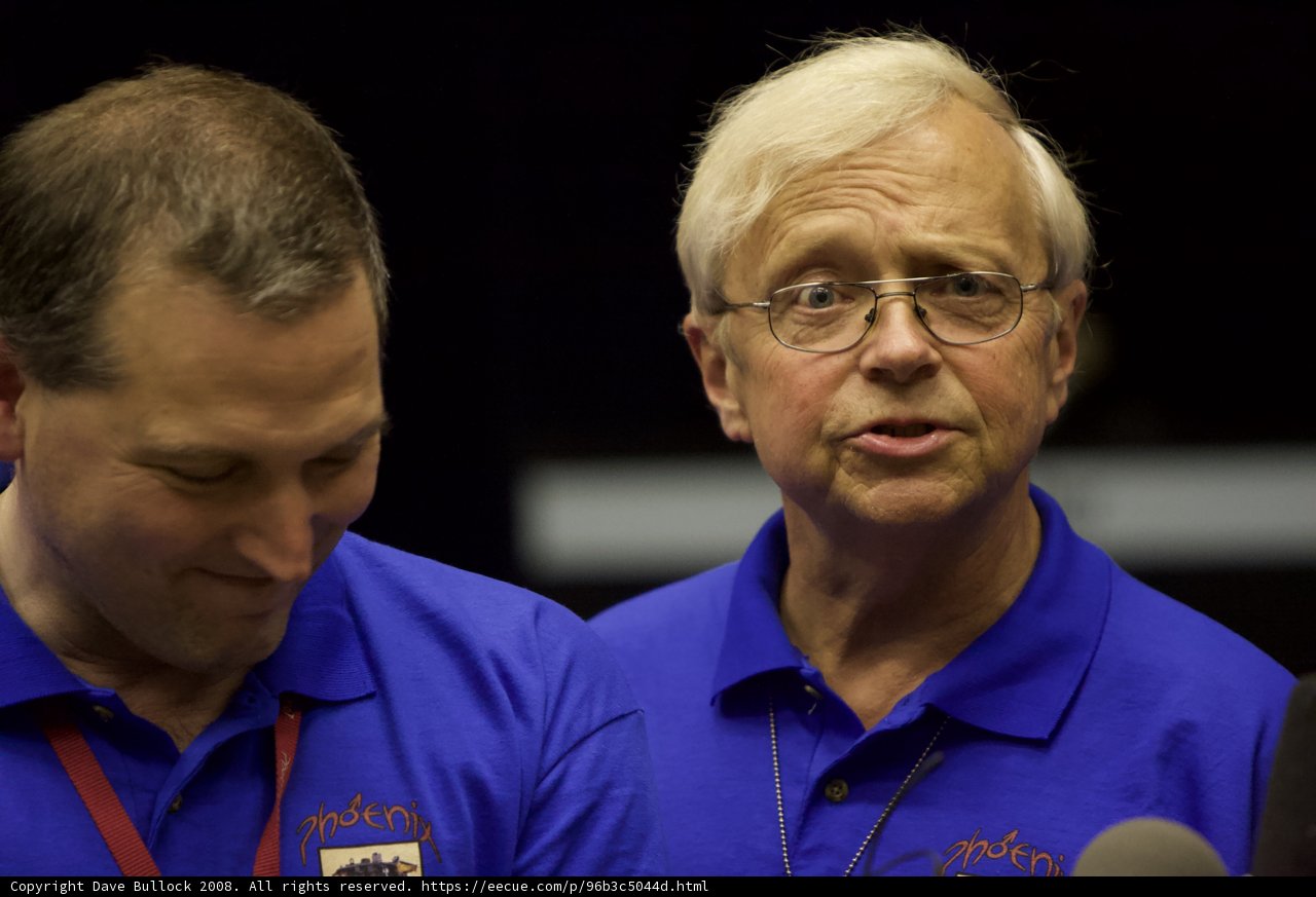Two Men in Blue Shirts and Glasses Standing Together