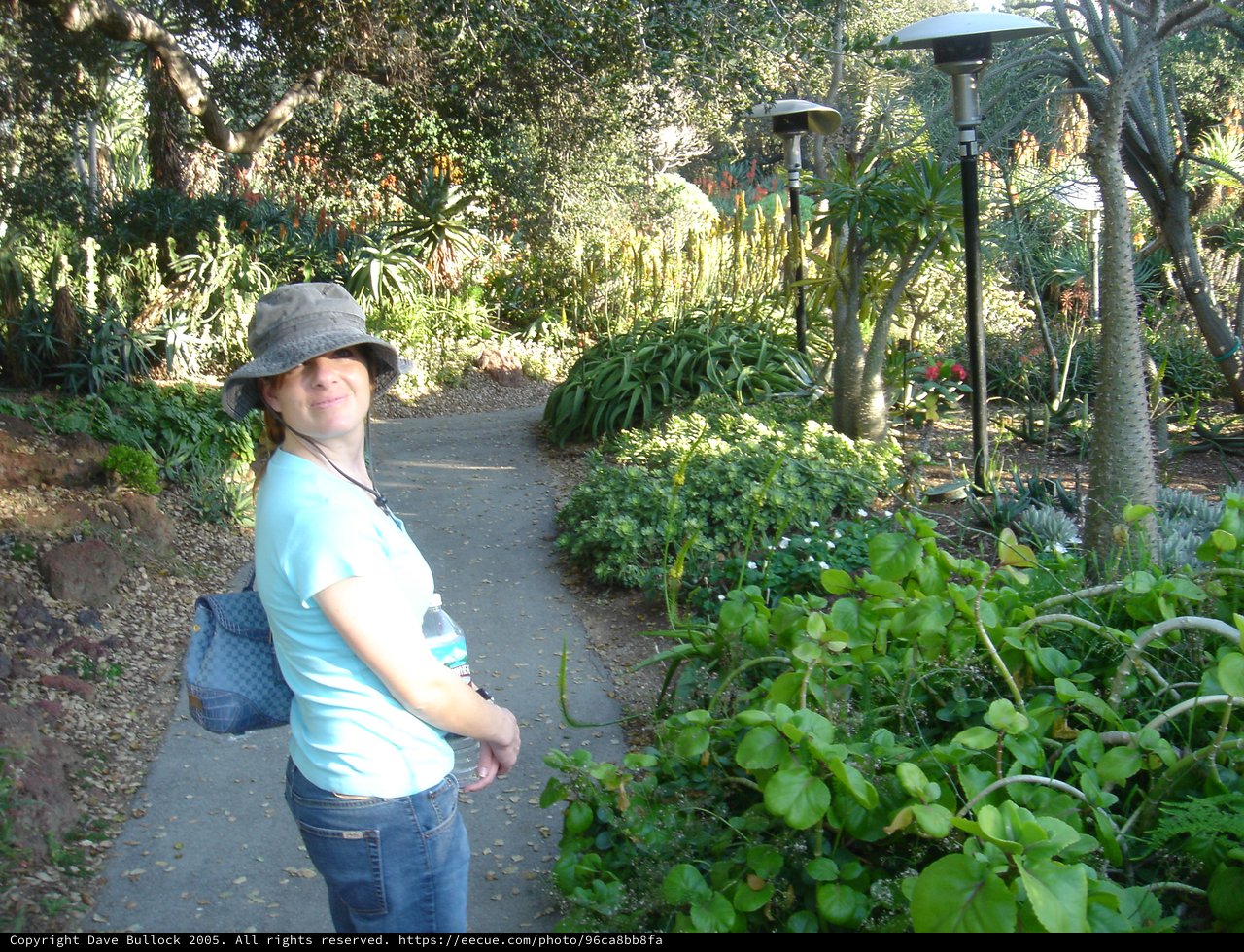 Woman Smiling on Lush Botanical Garden Pathway