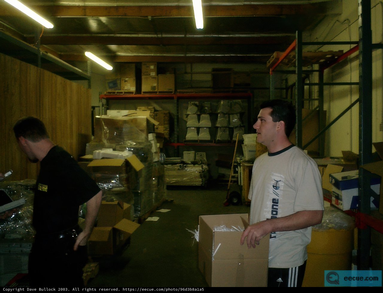 Two Men in a Warehouse Surrounded by Cardboard Boxes