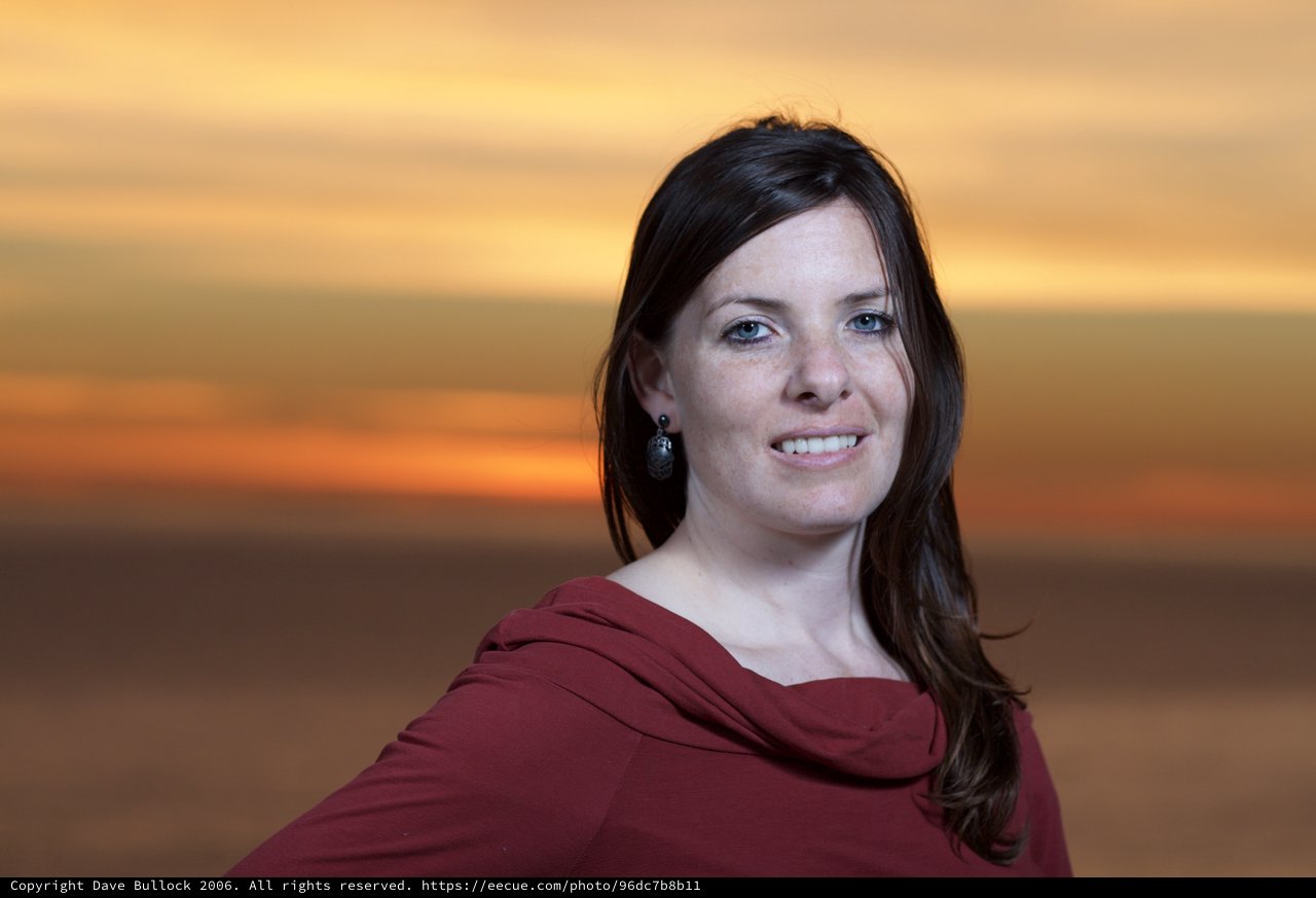Woman Smiling Against a Vibrant Sunset Sky