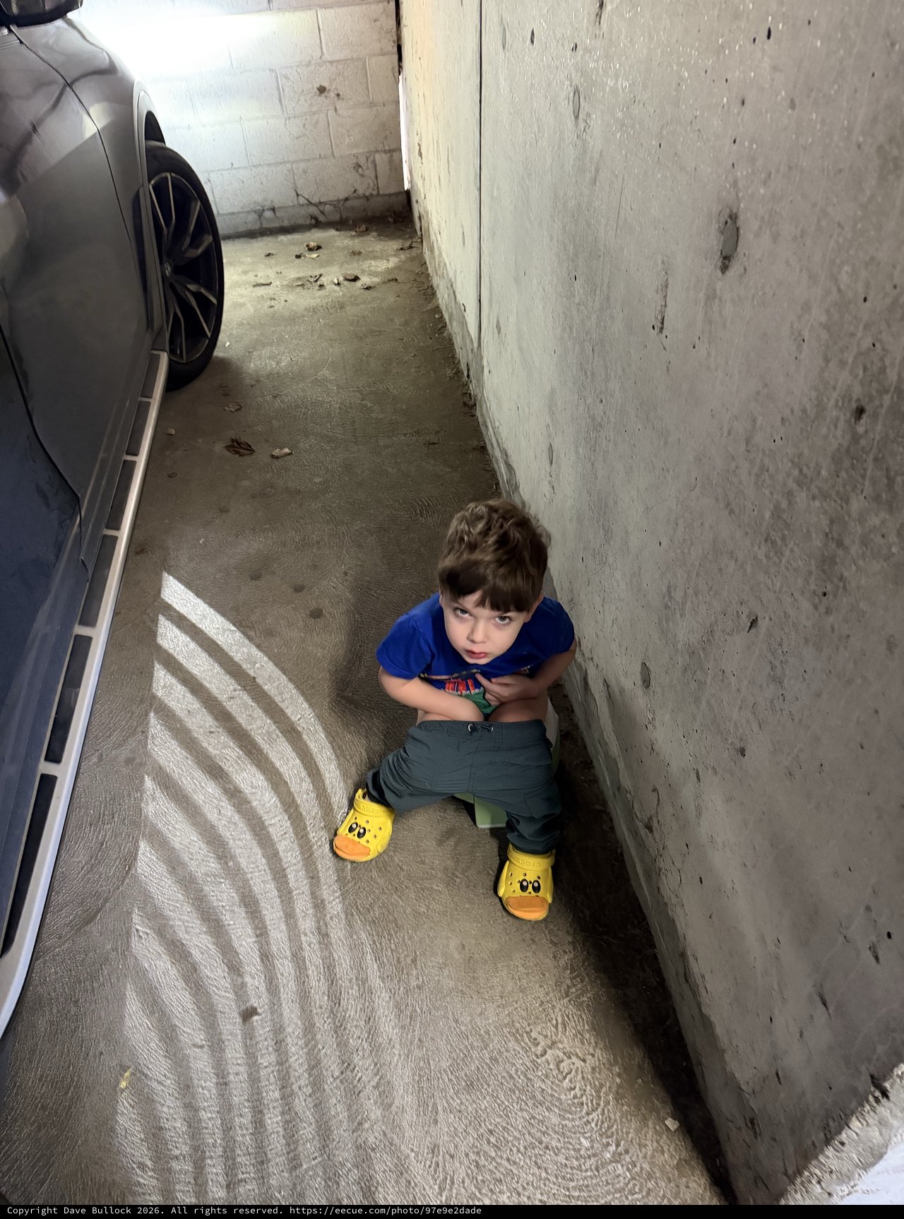 Young Child Sitting in Narrow Parking Garage Space