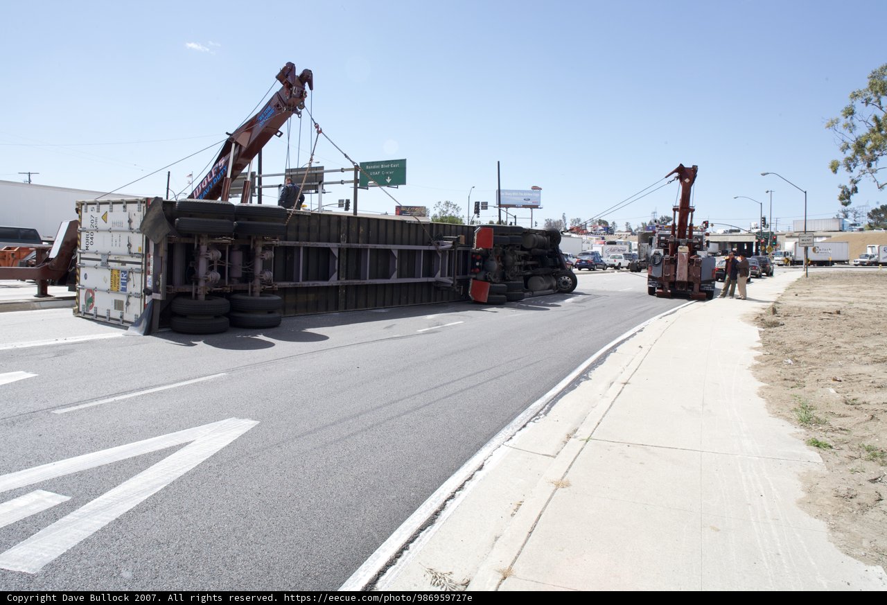 Crane lifting overturned truck on the street