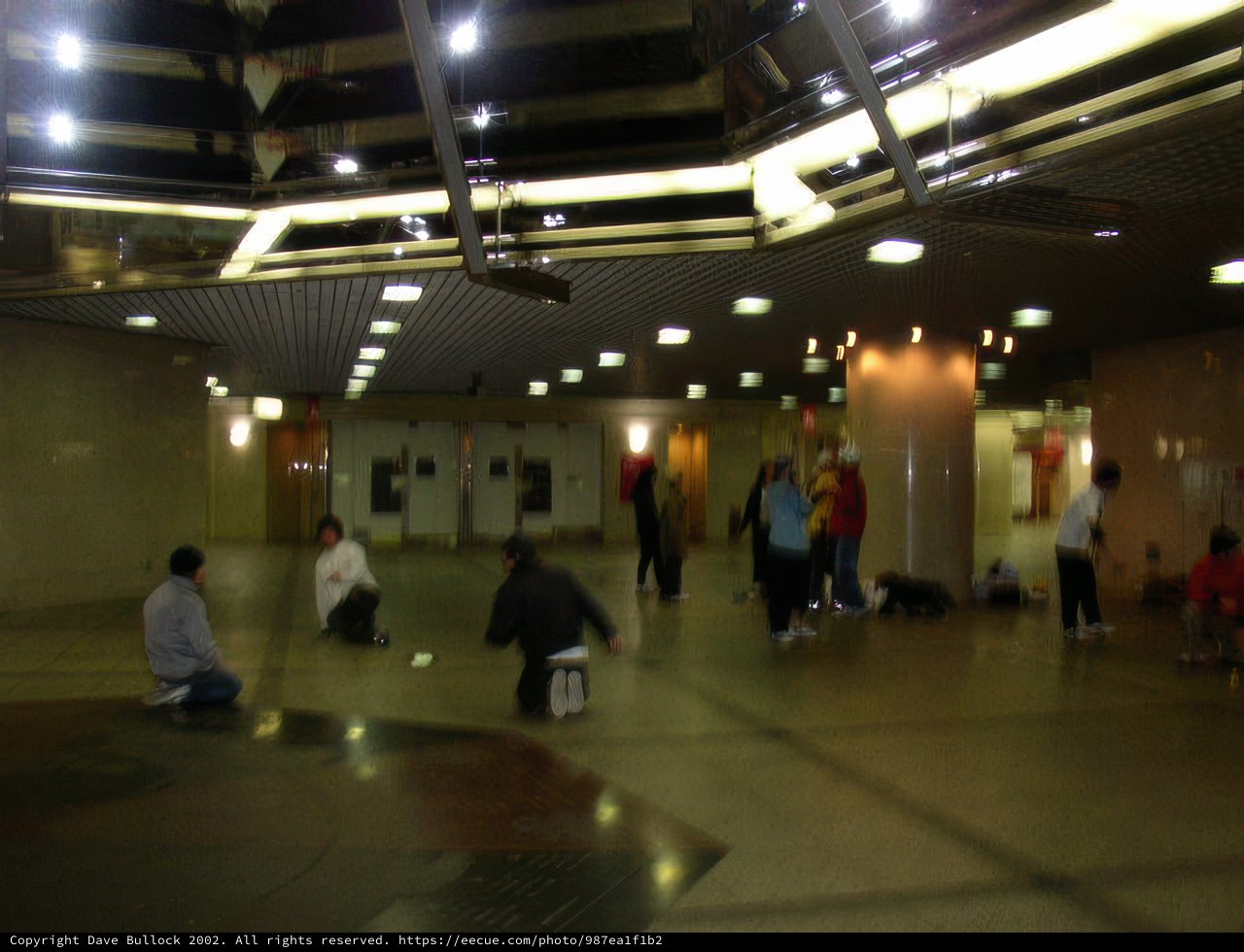 A Group of People Huddle Together on the Airport Floor
