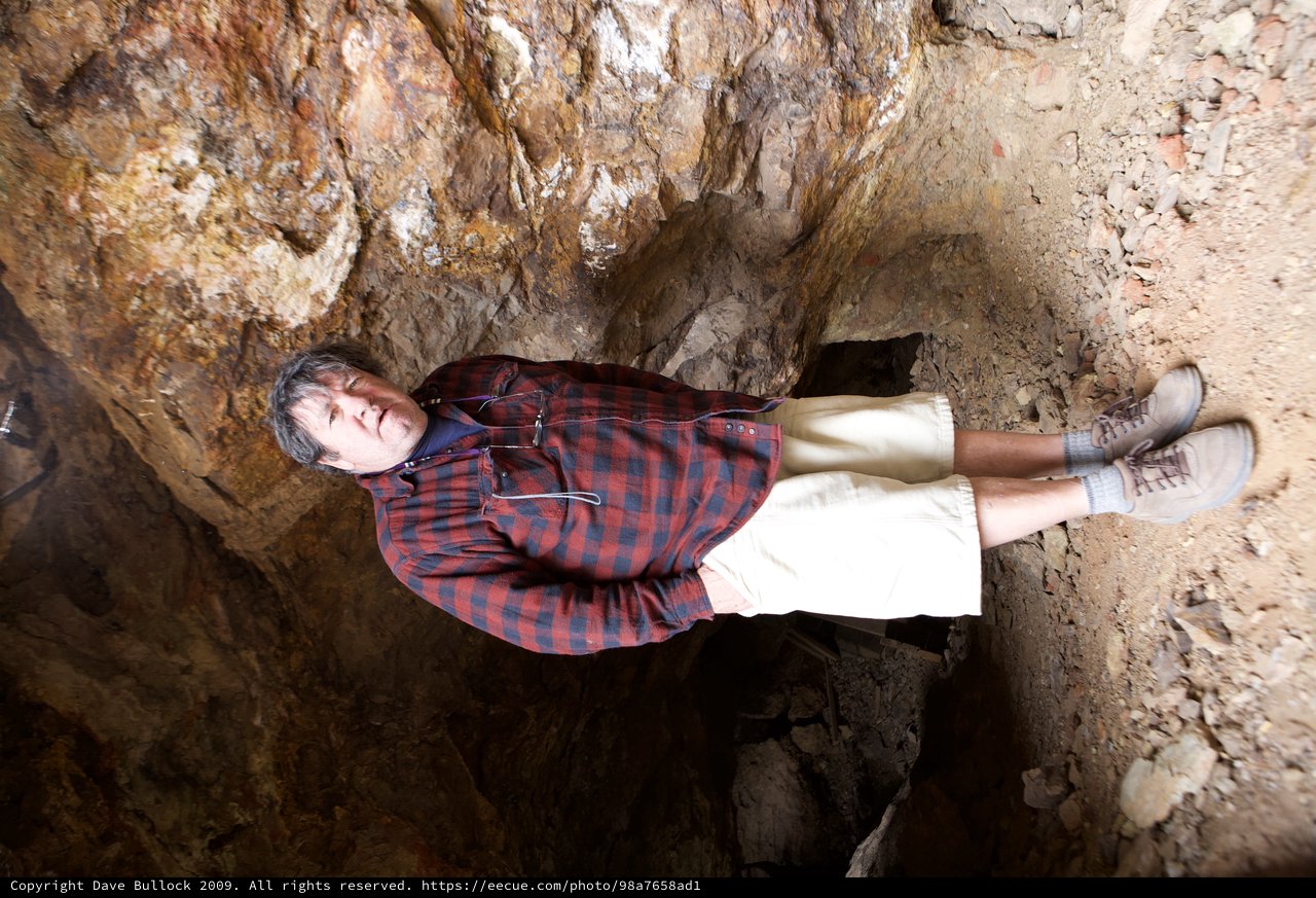 Man Standing Inside a Rocky Cave Entrance