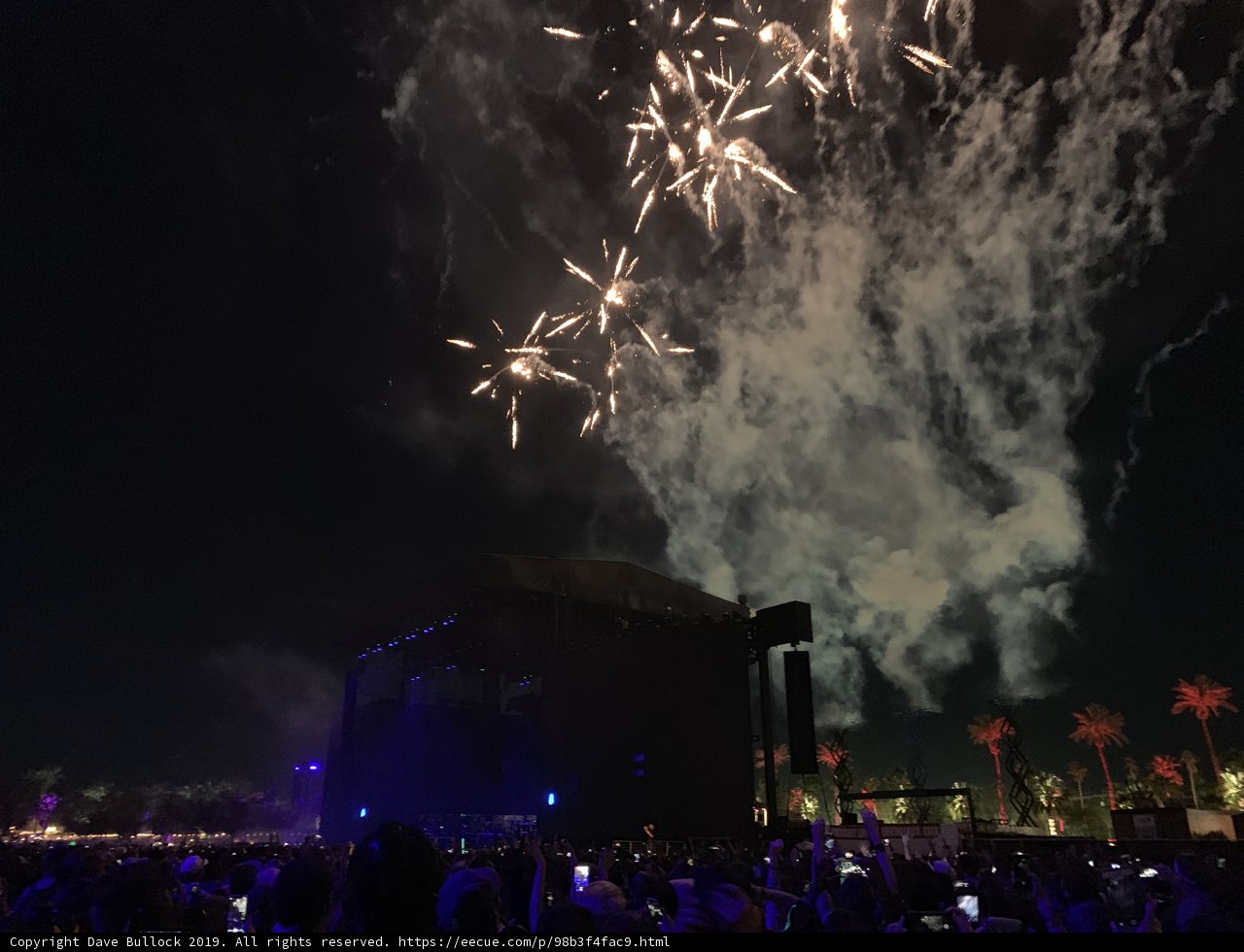 Fireworks Illuminate the Night Sky over a Concert Crowd