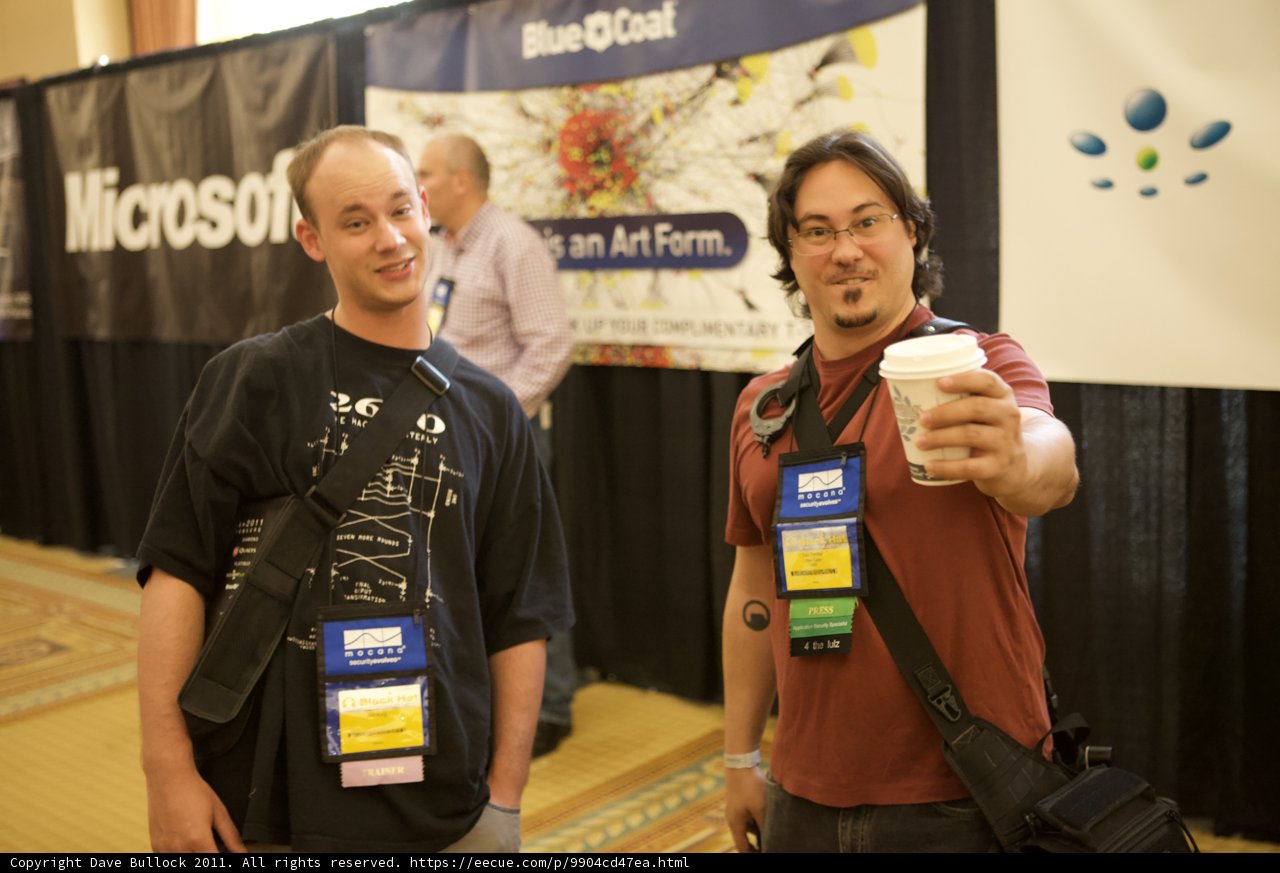 Two Men Strike a Pose Under a Banner