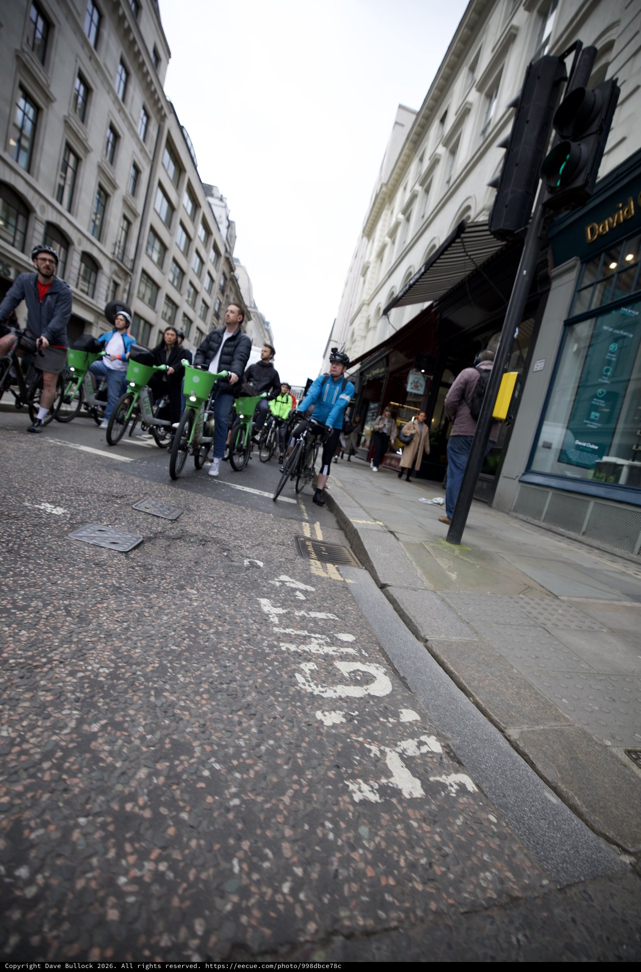 Bike Share Cyclists Riding Through London Shopping Street