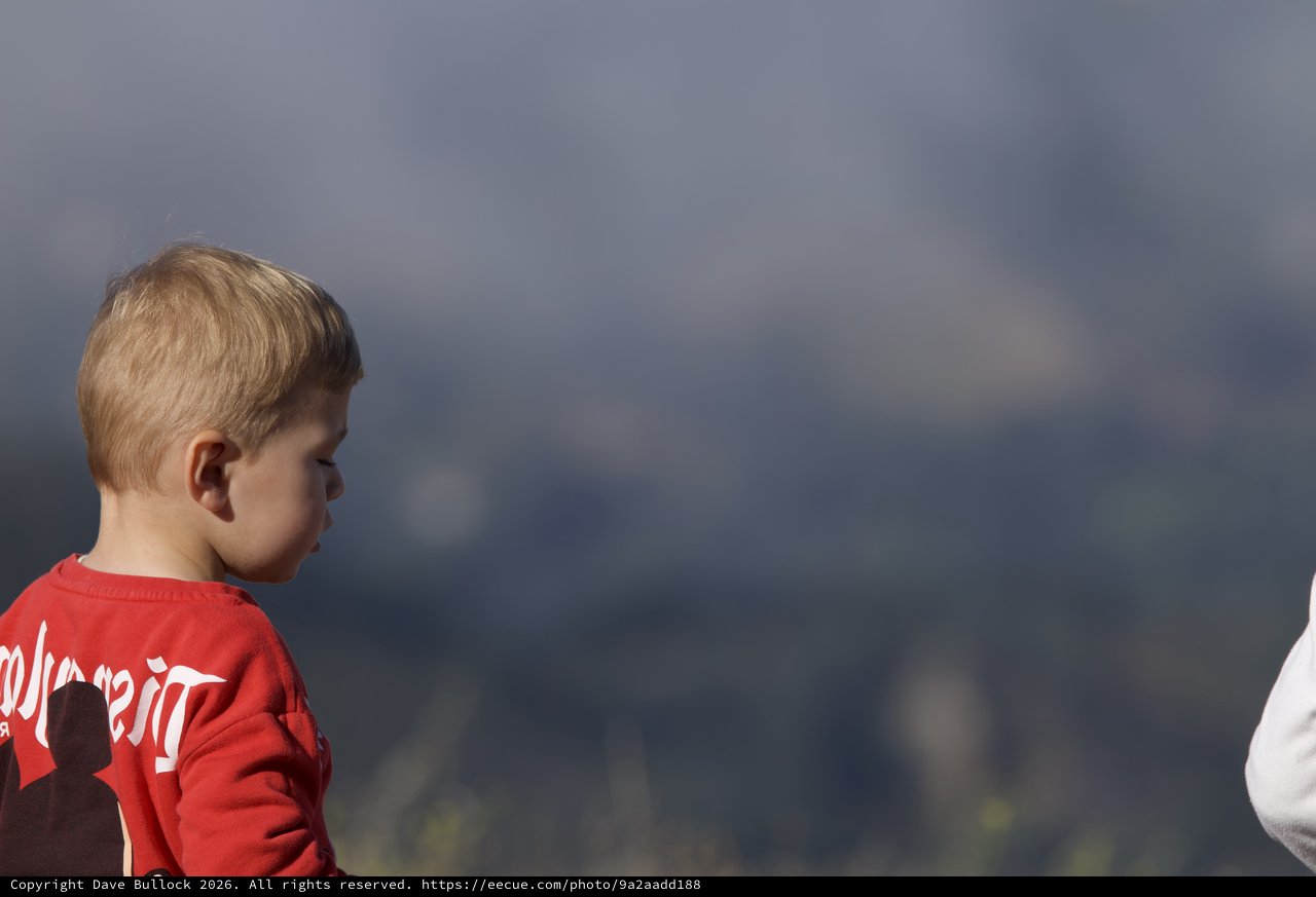 Young Boy Gazes Thoughtfully Against Stormy Mountain Sky