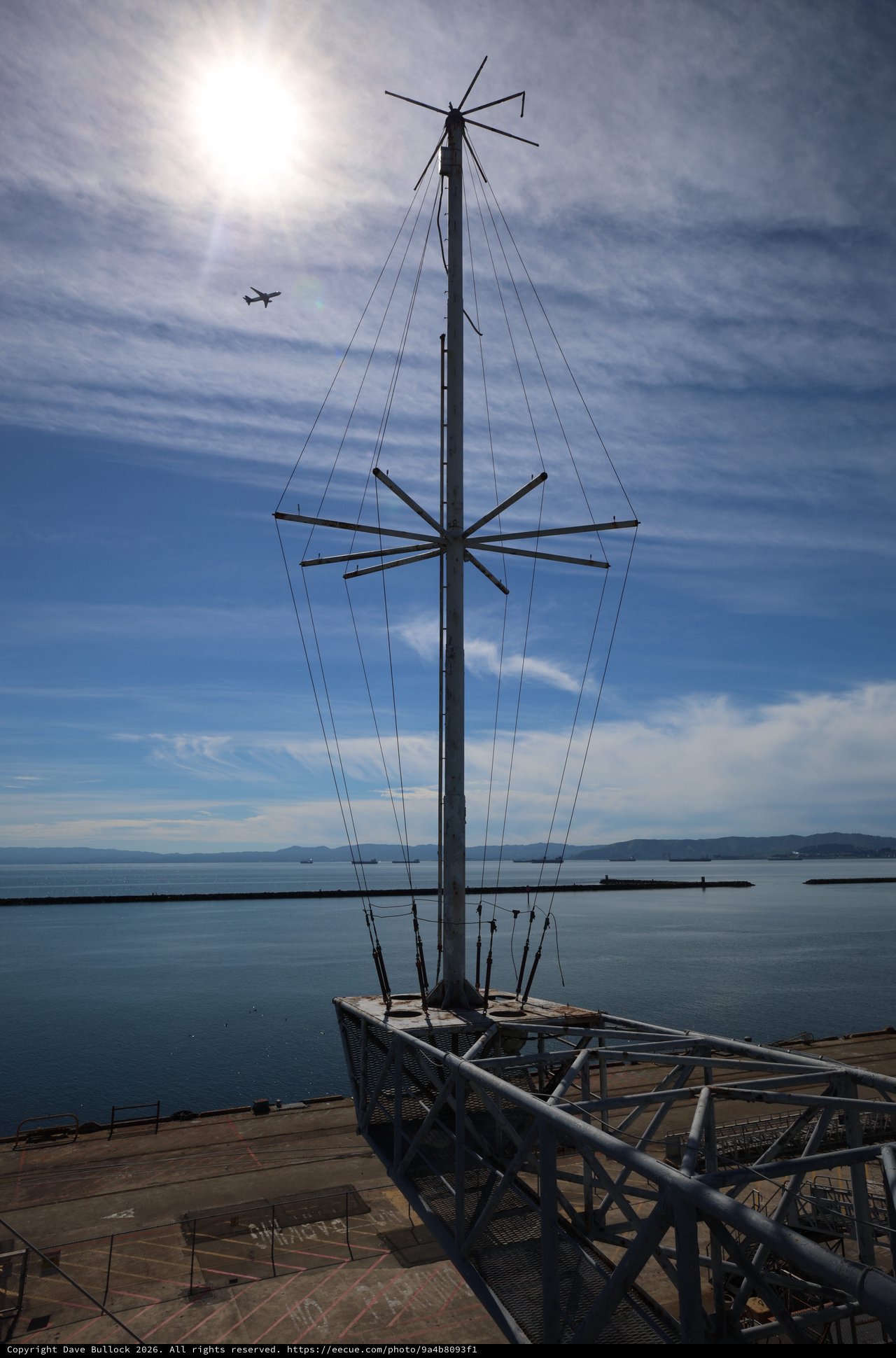 Silhouetted Ship Mast Against Coastal Skyline