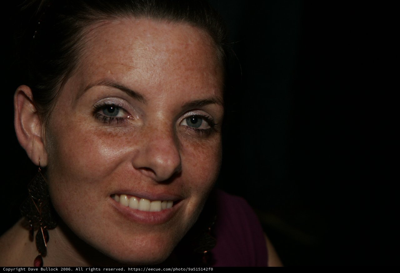 Smiling Woman with Freckles in Dark Setting