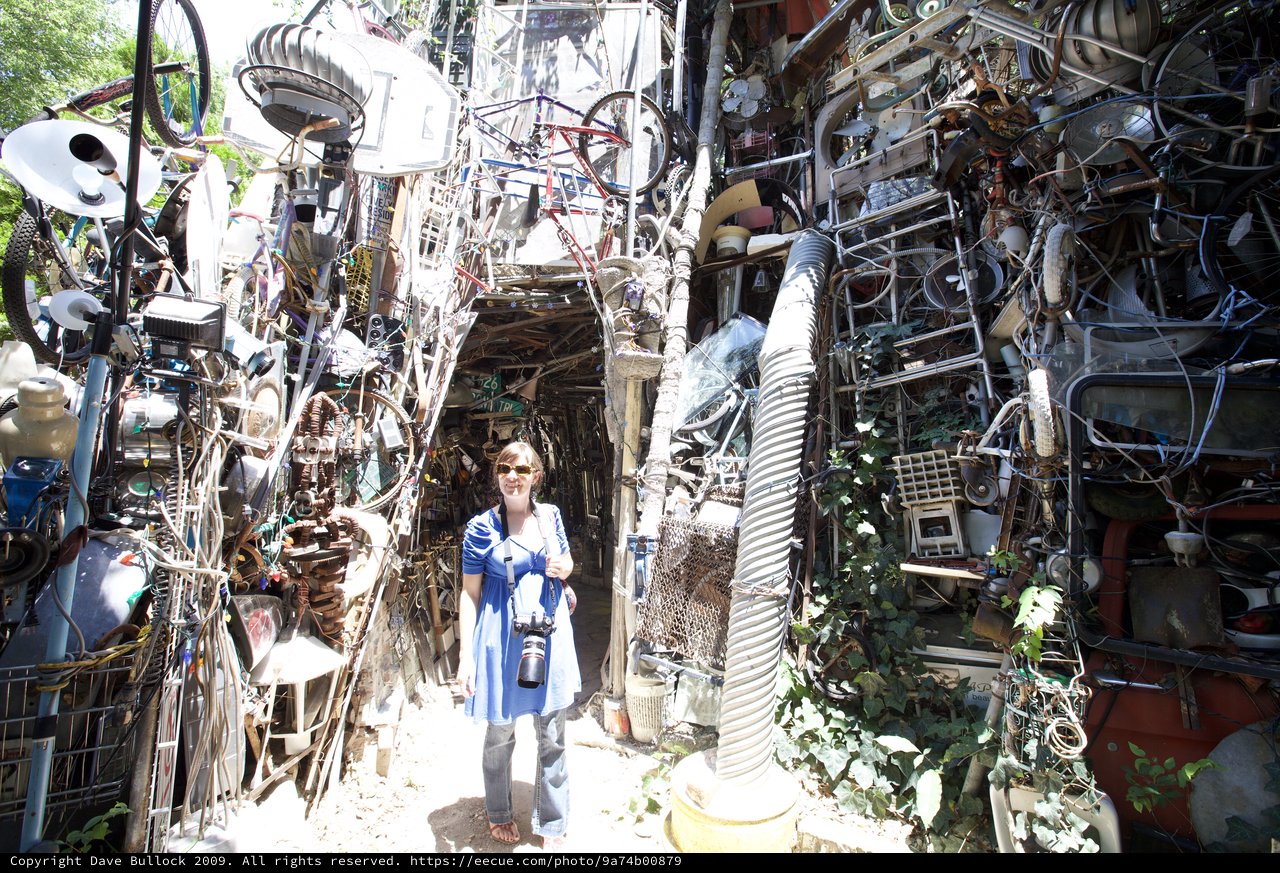 Woman Photographer Dwarfed by Cathedral of Junk Austin