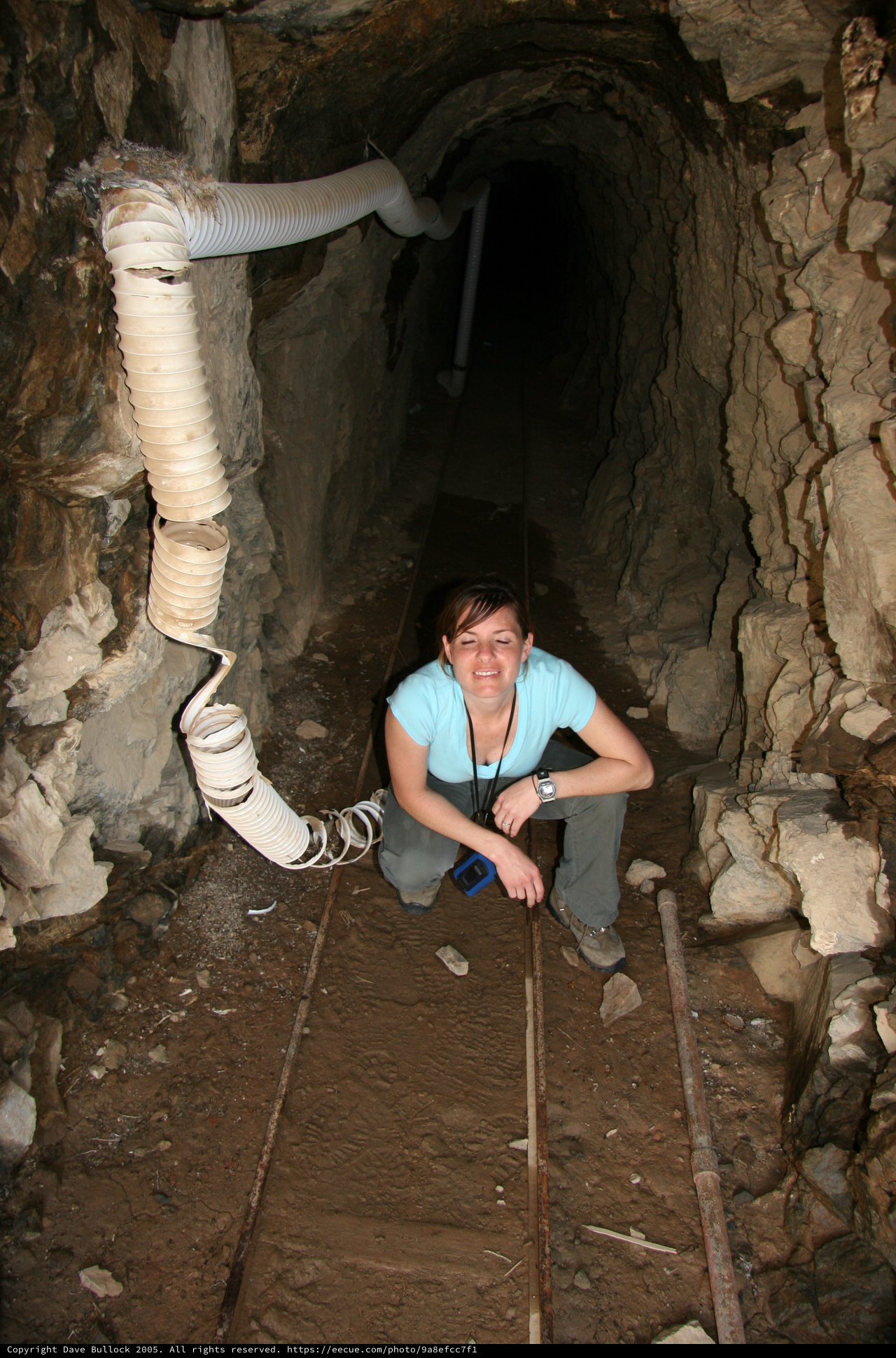 Explorer Crouching in Historic Underground Mine Tunnel
