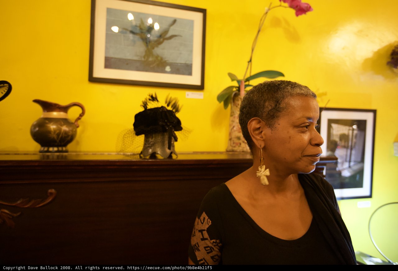 Woman in Black Shirt Poses in Front of a Yellow Wall