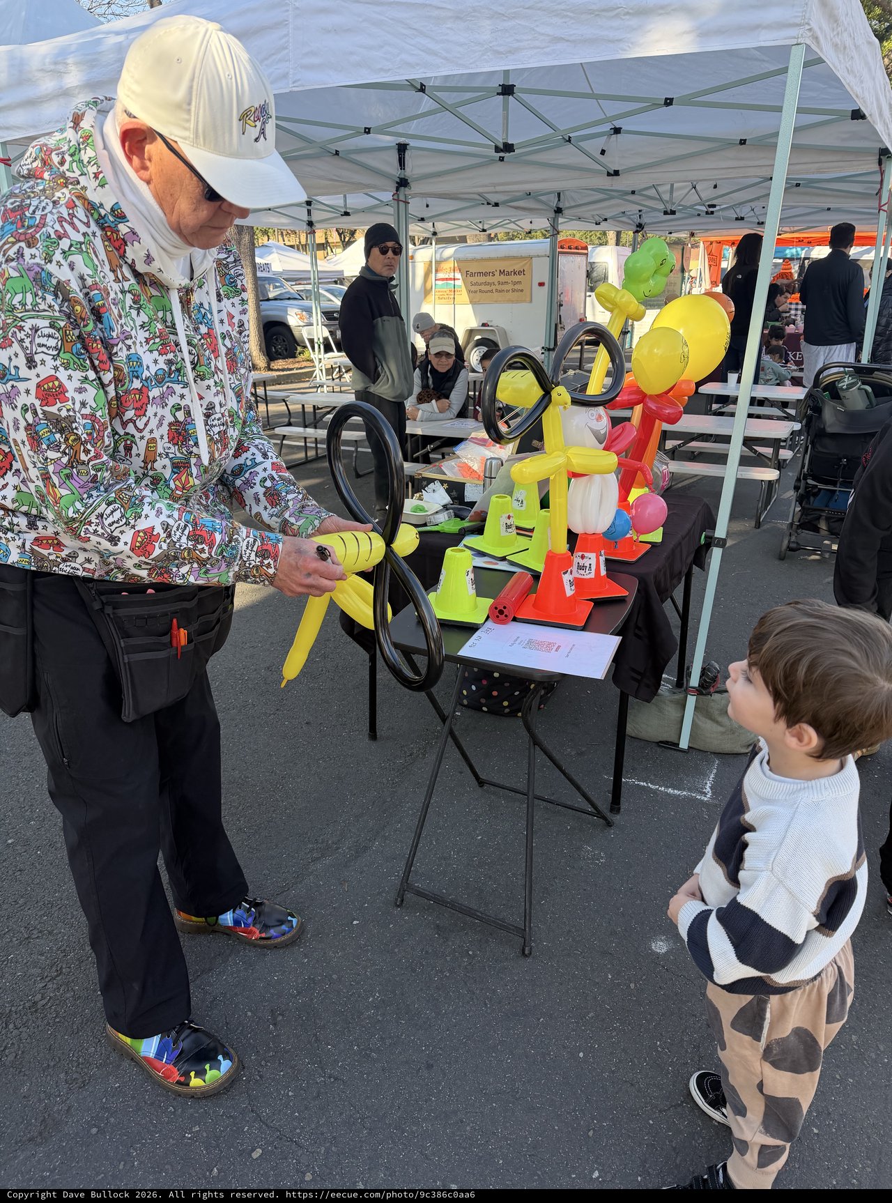 Balloon Artist Delights Young Child at Farmers Market