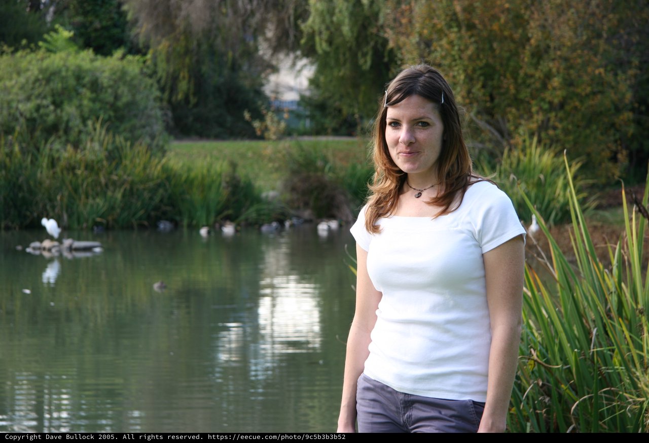 Young Woman Smiling by a Tranquil Park Pond