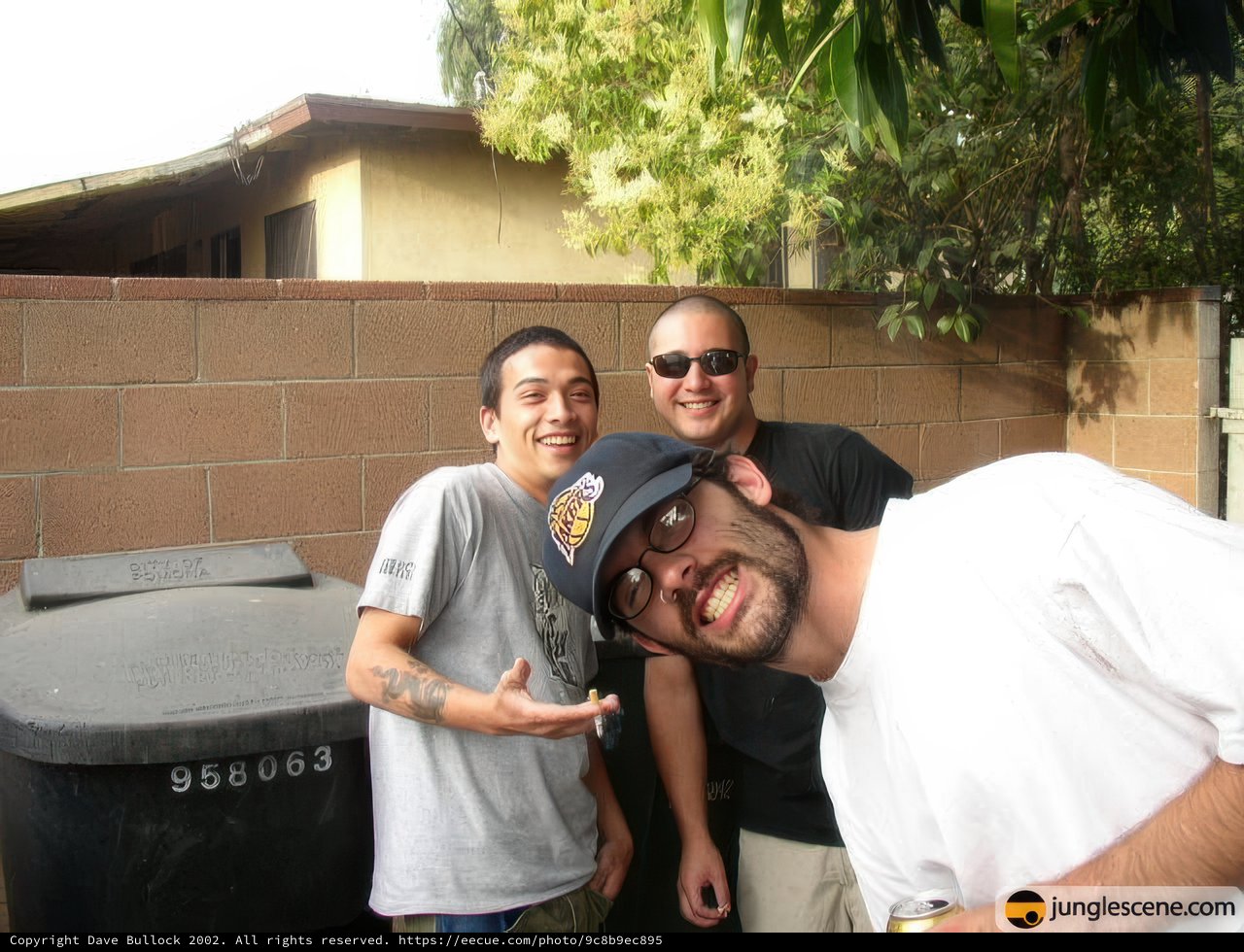 Three Men Strike a Pose in Front of a Trash Can