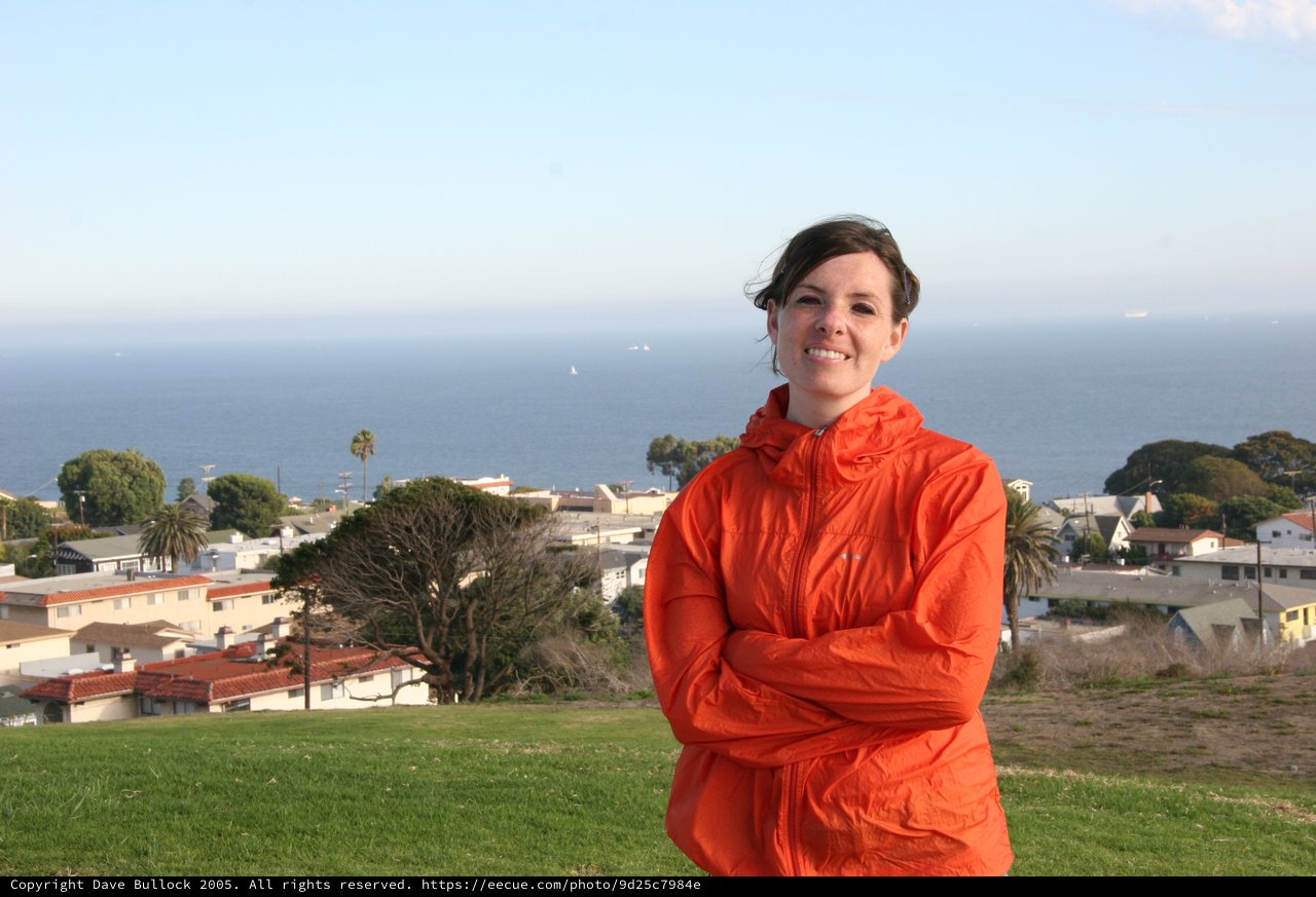 Woman in Orange Jacket Overlooking Coastal Town