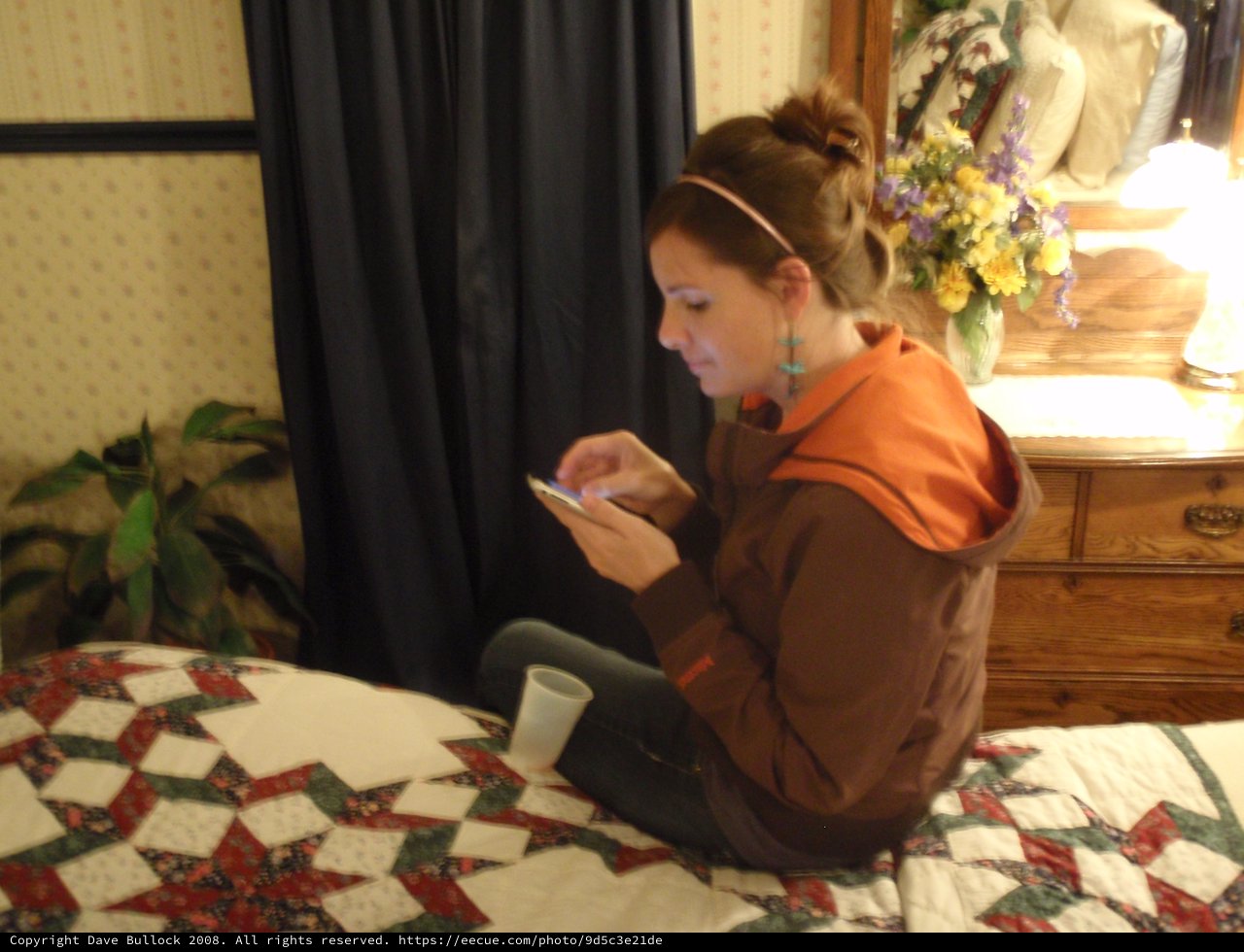 Young Woman Texting on Phone in Cozy Bedroom