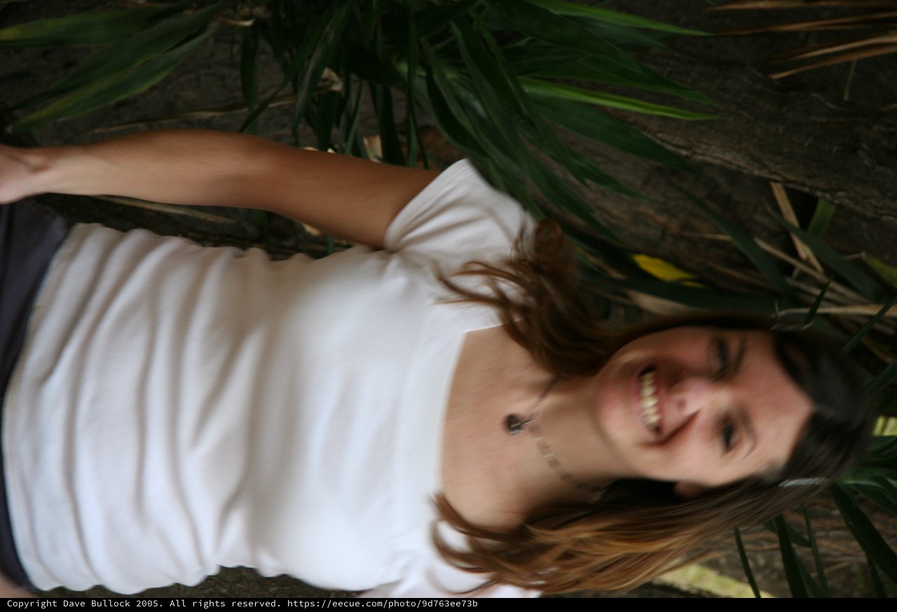Smiling Woman in White Tee Among Tropical Foliage