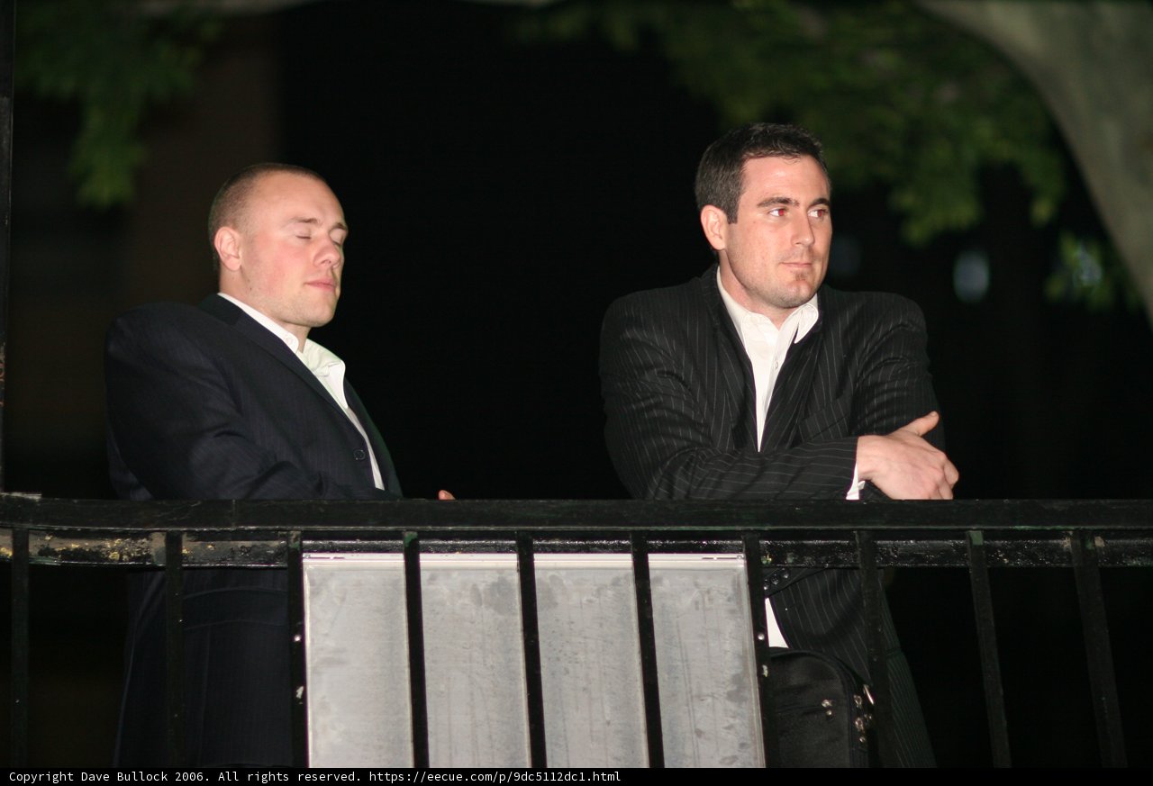 Two Men Standing on Balcony in Formal Attire