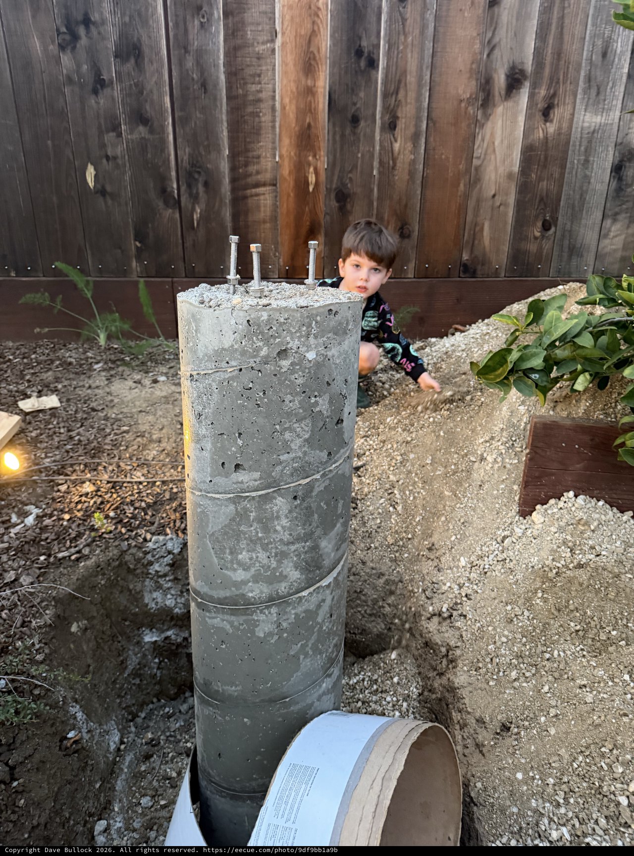 Young Boy Explores Concrete Pier Foundation in Backyard