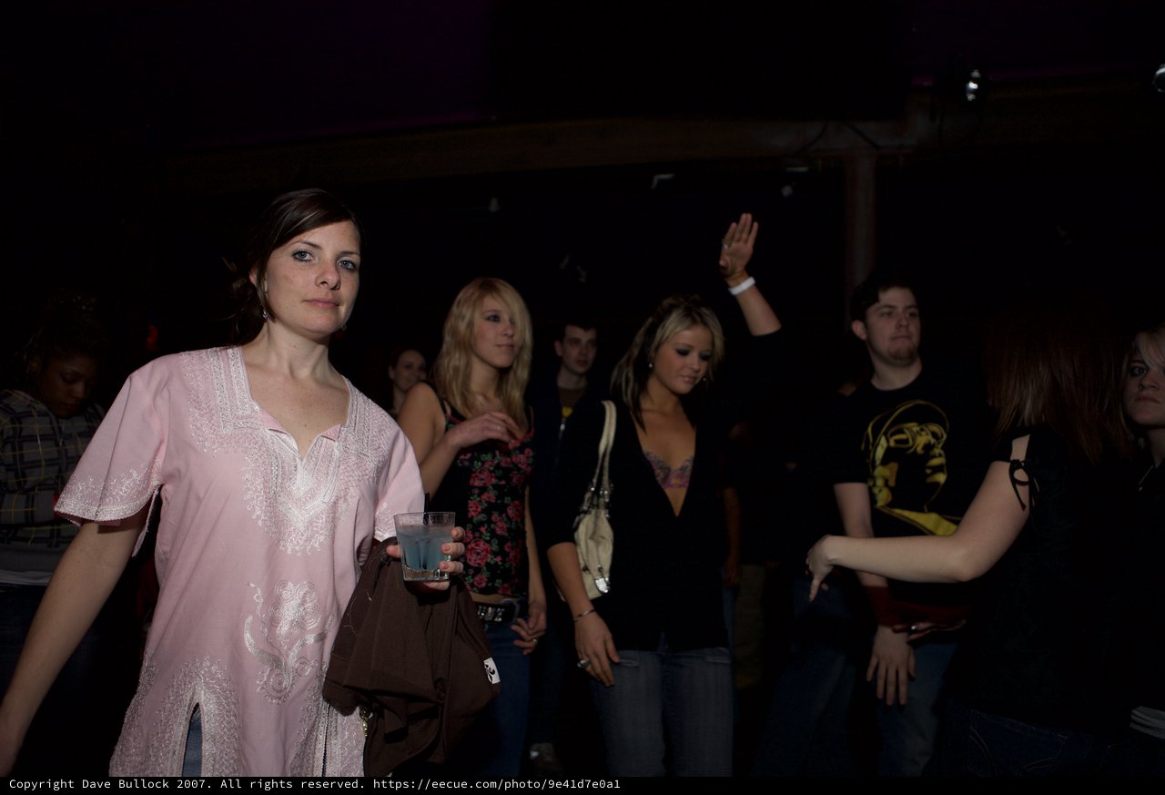 Young Woman at Nightclub Glances at Camera