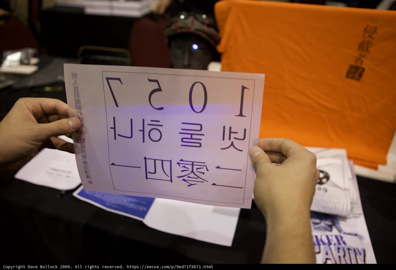 The Sign of 1057 Caption: A man proudly holds up a sign displaying the symbolic number 1057, accompanied by two others in helmets. The intricate calligraphy and handwriting make the text all the more impressive.