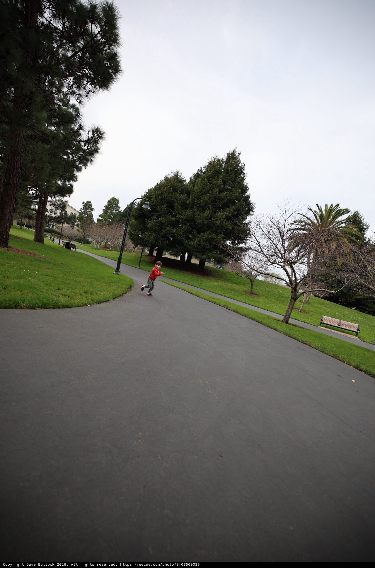 Child Running on Winding Park Path on Overcast Day