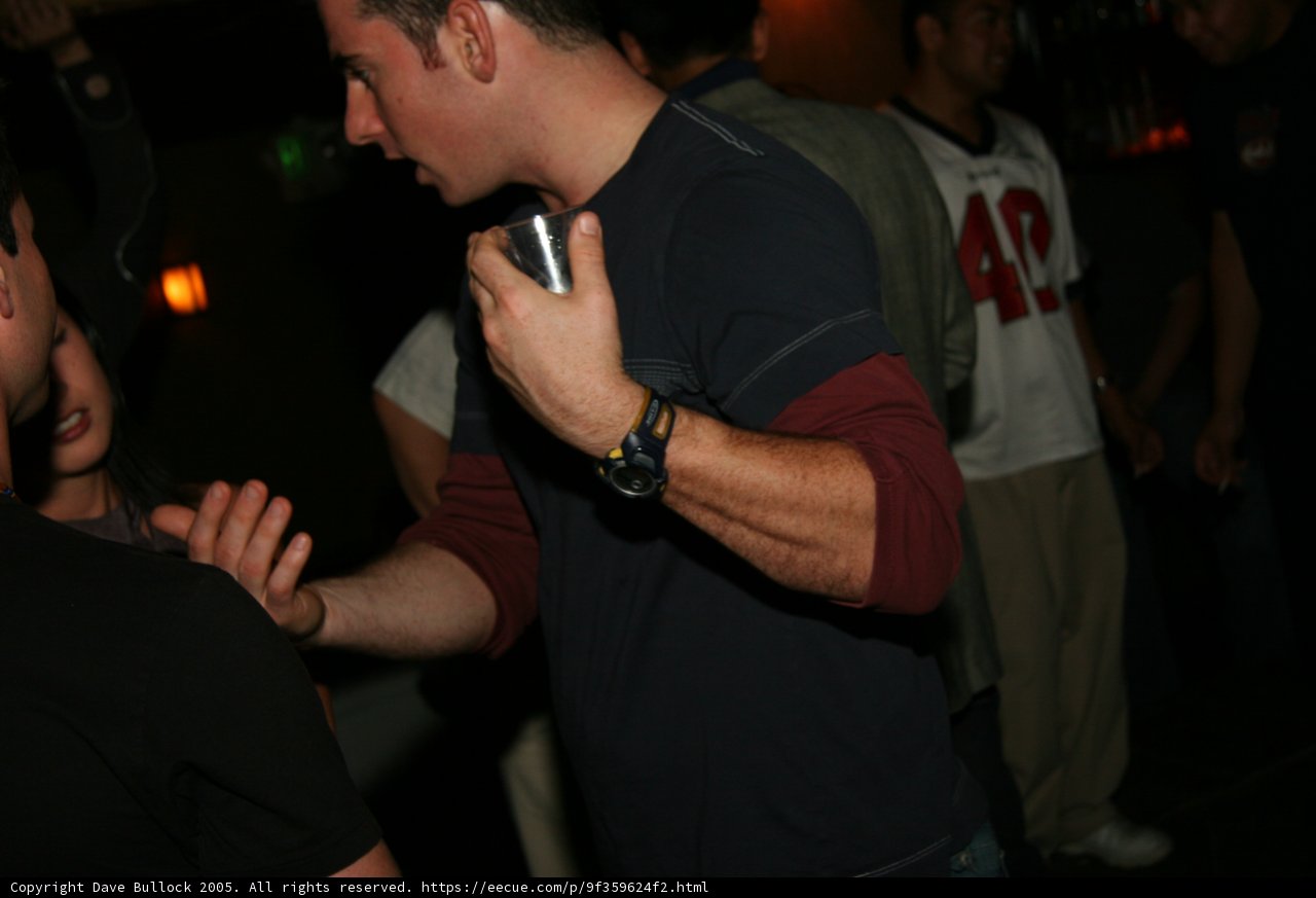 Black-shirted man checks watch at the club