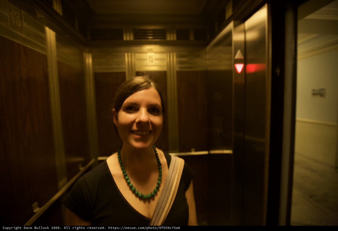 Smiling Woman in Warmly Lit Vintage Elevator