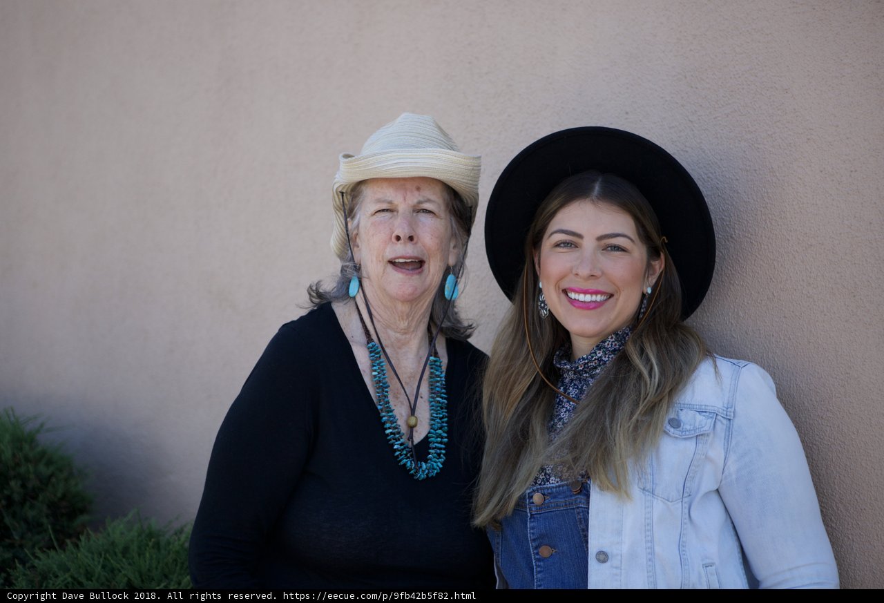 Two Women with Hats and Earrings Smiling for the Camera