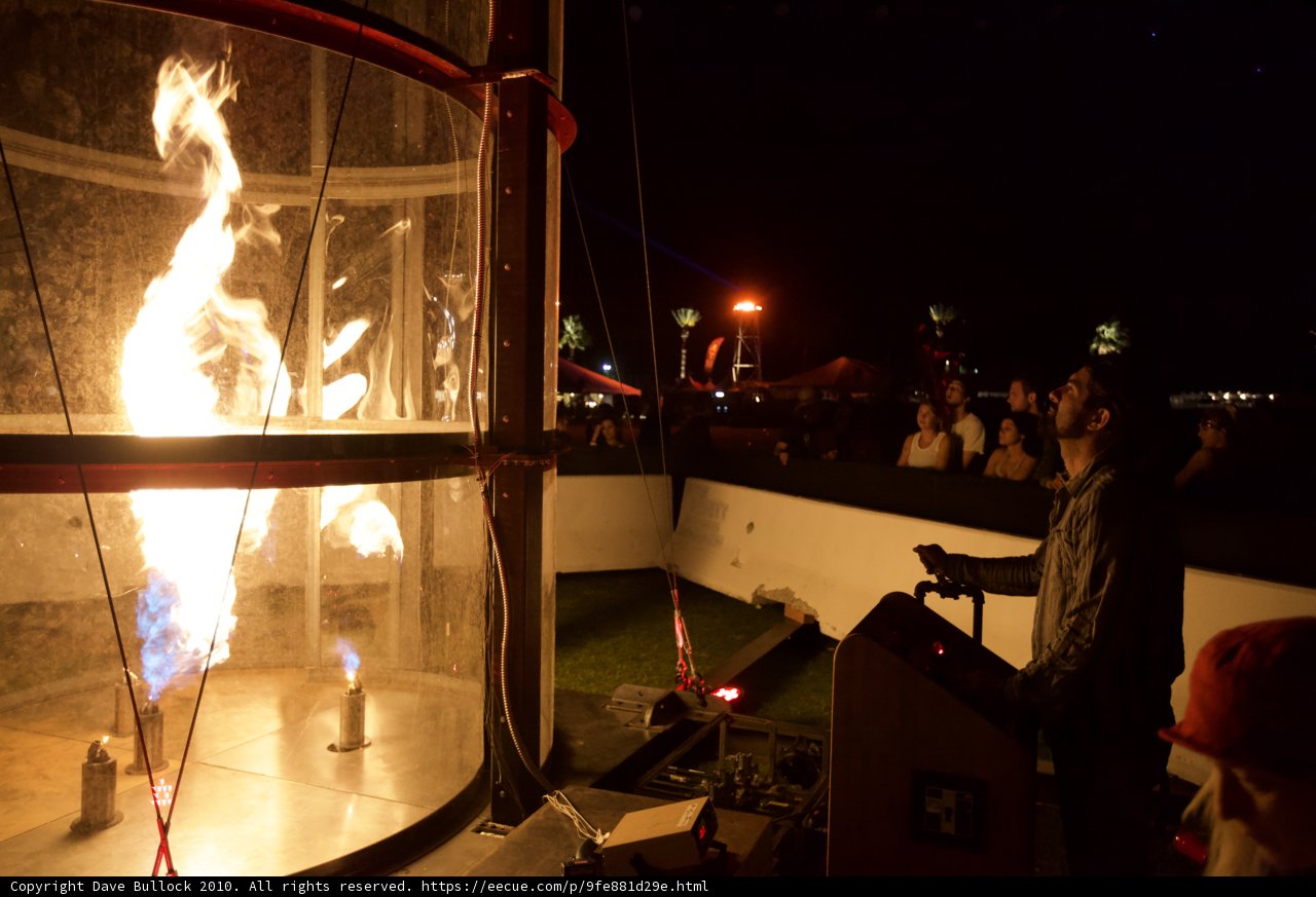 Man Standing in Glass Box Amidst Fire