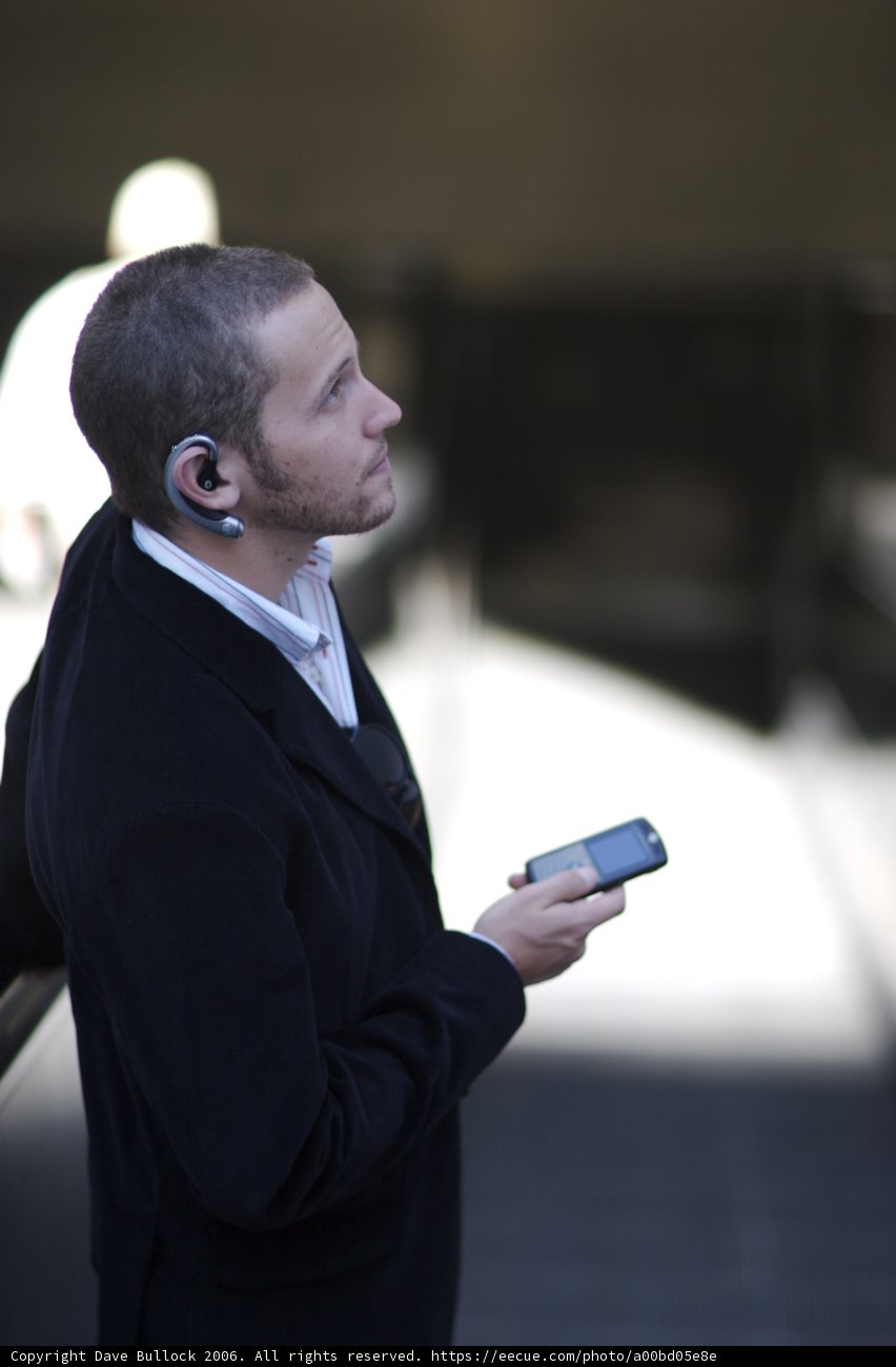 Businessman using mobile phone Caption: A man dressed in a suit and tie uses his mobile phone to text while on a break from a consumer electronics shoot in 2006.