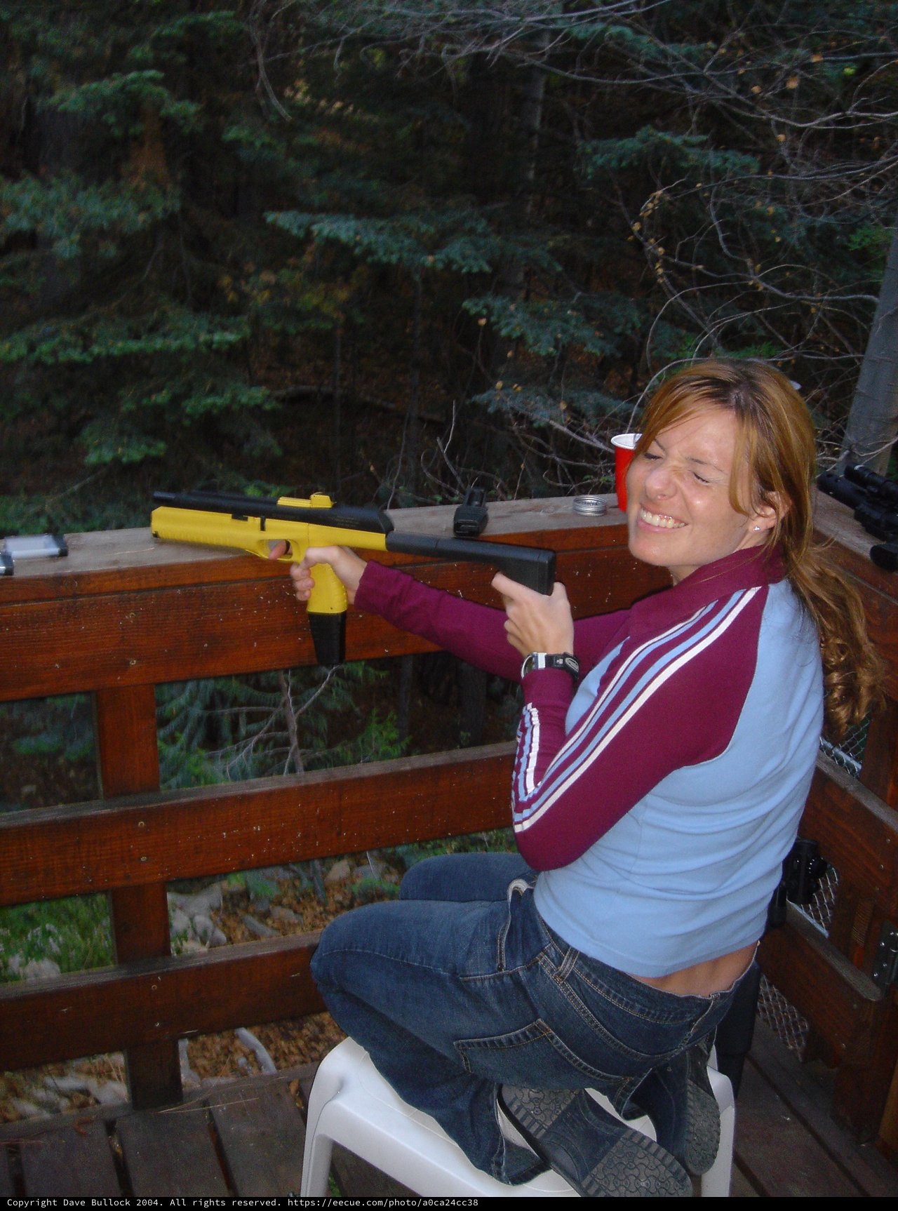 Woman Smiling with Yellow Air Gun on Wooden Deck