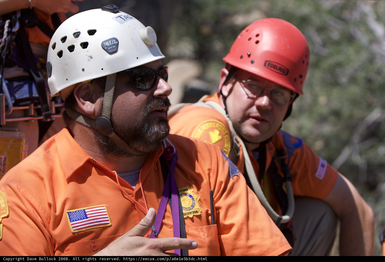 Two Men in Orange Shirts Wearing Hardhats