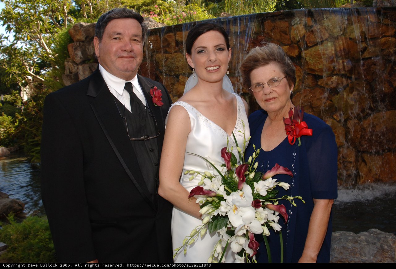 Bride Poses With Parents at Garden Wedding