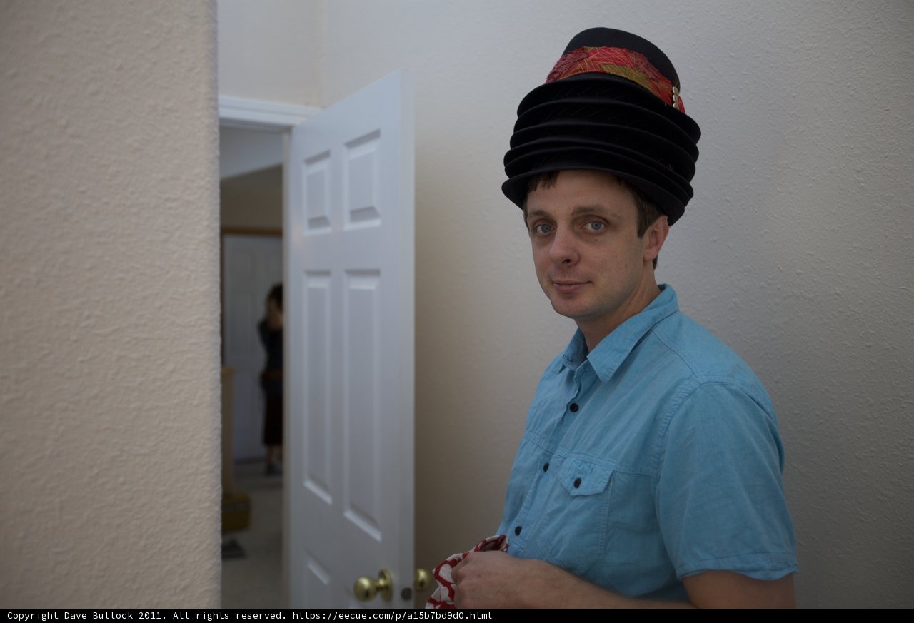 Hat-wearing man stands at door