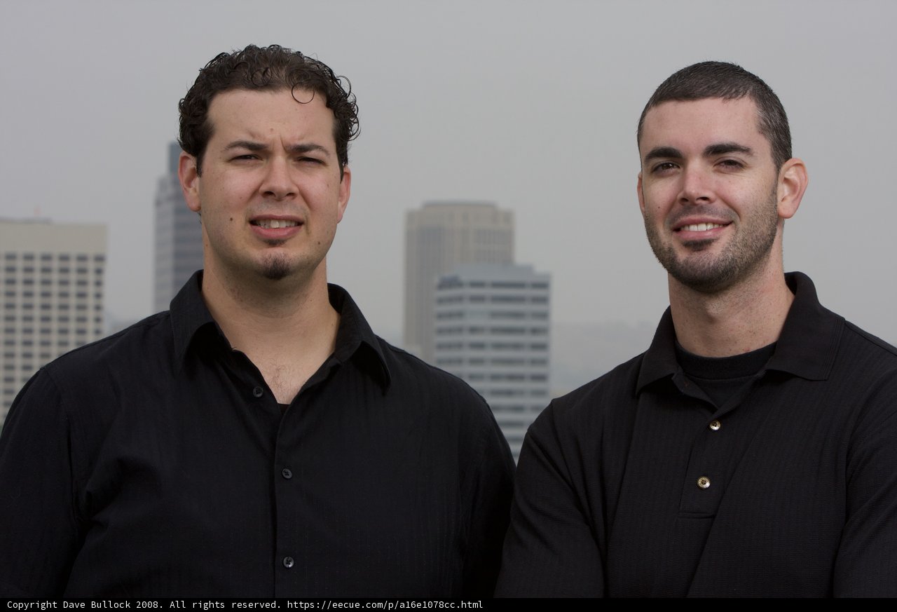 Two Men Smiling in Front of Skyscraper