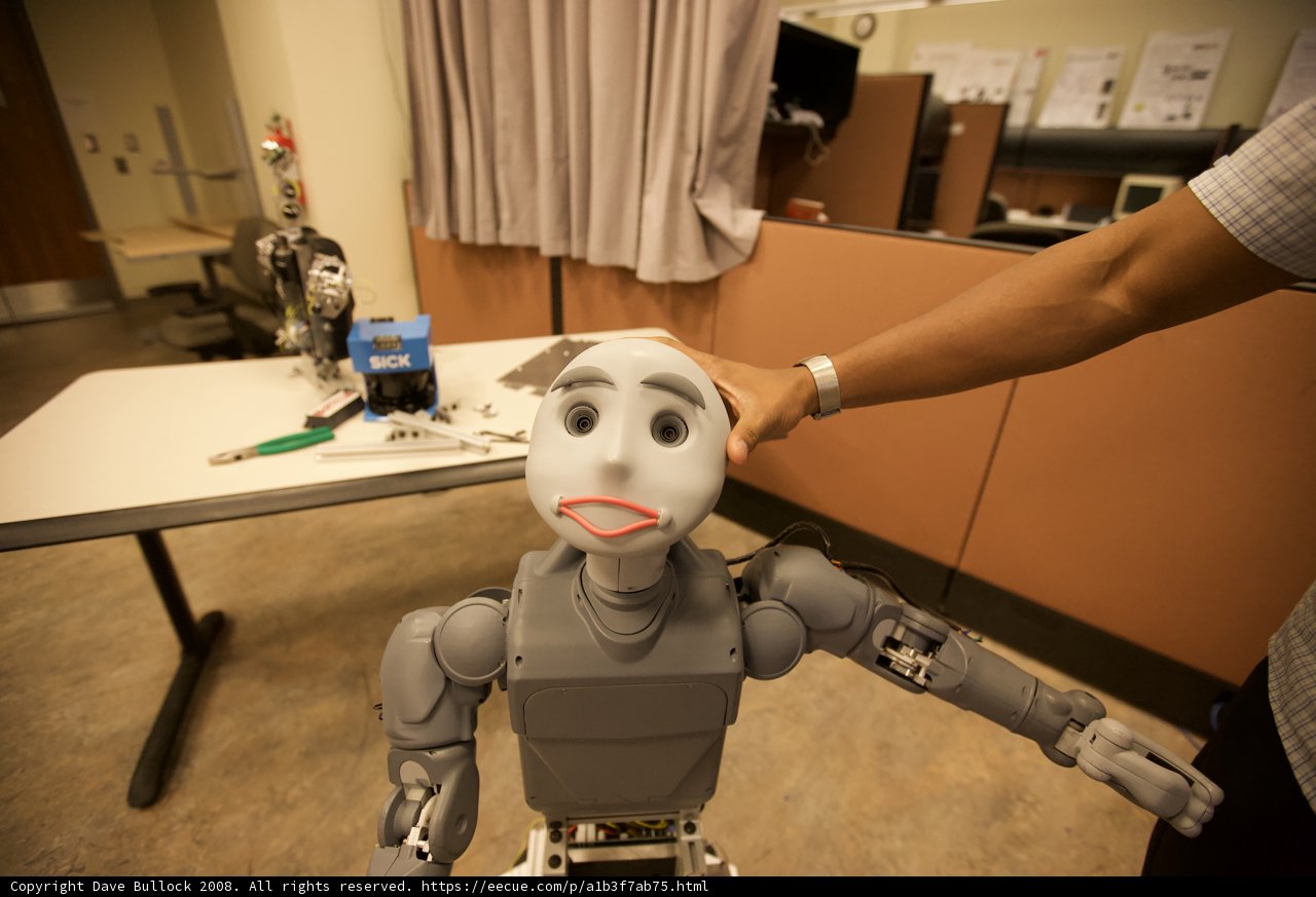 Man holding a Plywood Robot in a Room