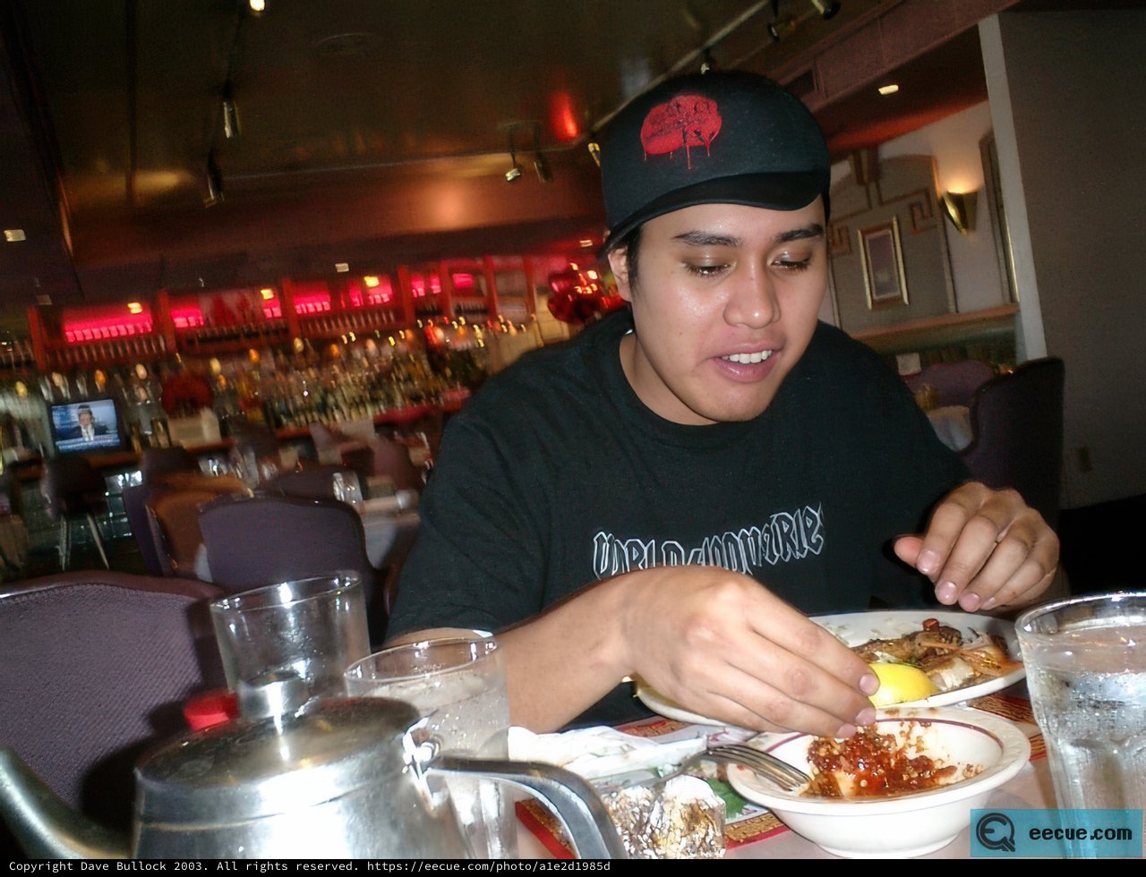 A Man in Black Hat Enjoying a Meal at a Restaurant
