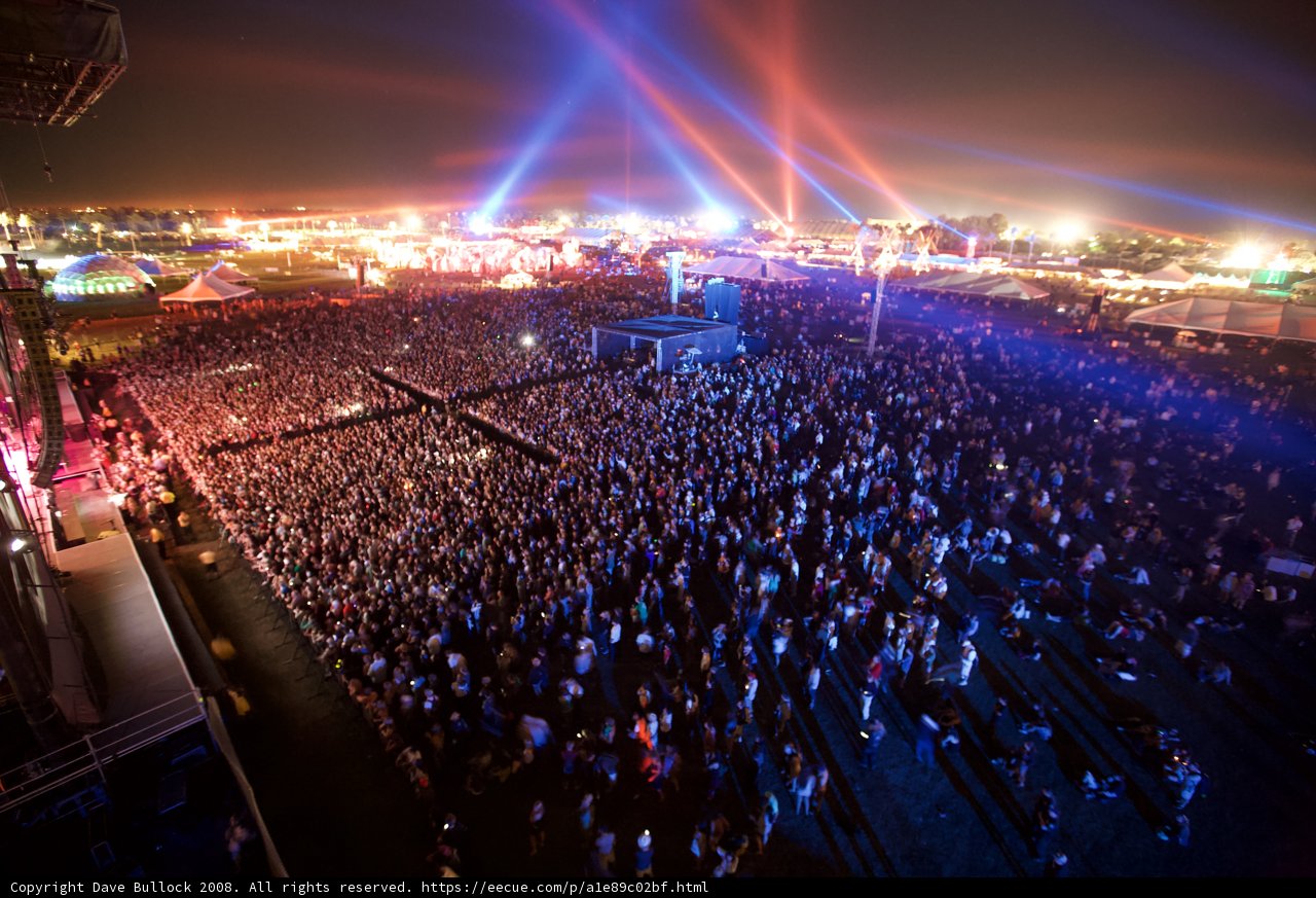 Coachella Rocks the Night Sky Caption: A massive crowd gathers under the bright lights of the stage, enveloped in the excitement of an unforgettable night at the 2008 Coachella music festival.