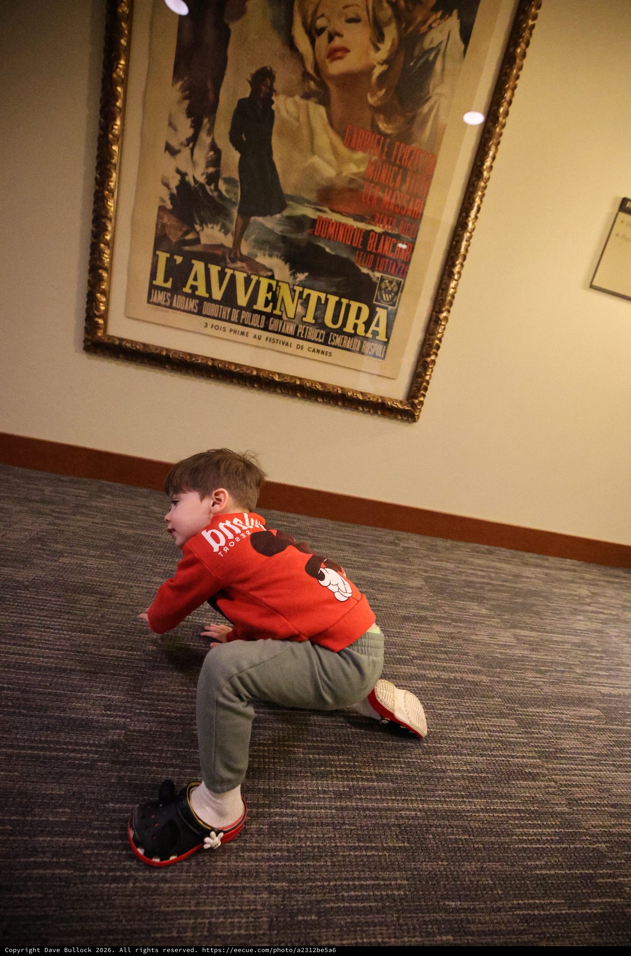 Child Playing Near Classic Film Poster in Lobby