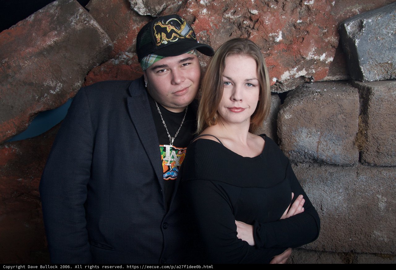 Two Adults Strike a Pose in Front of a Brick Wall