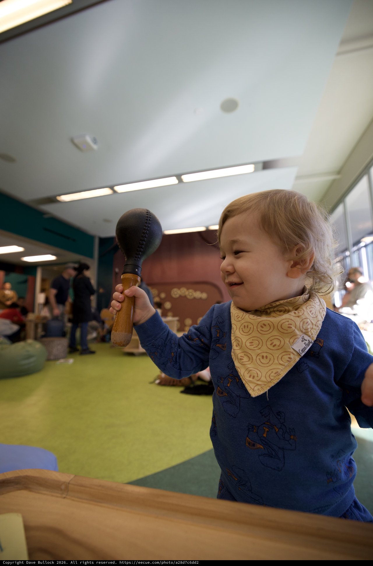 Joyful Toddler Playing with Wooden Toy at Children's Museum