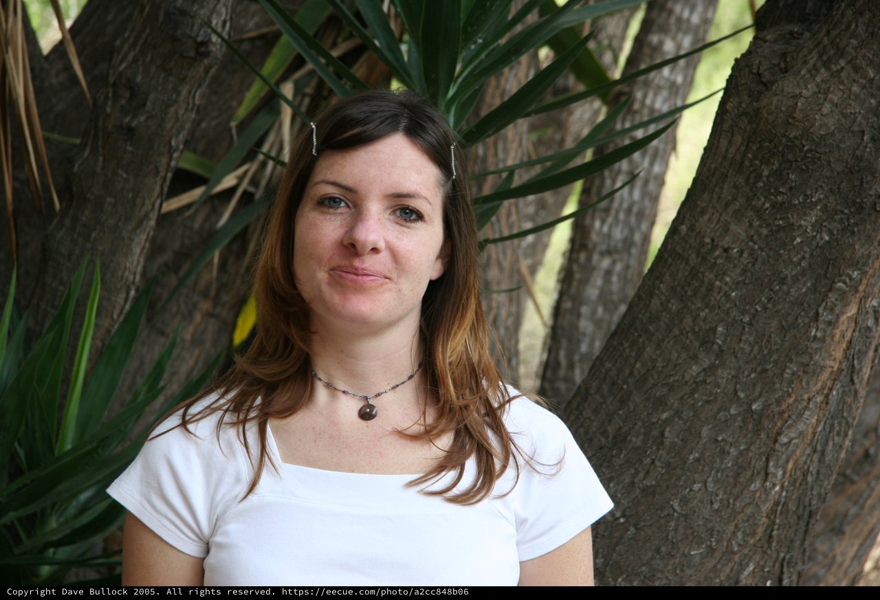 Woman Smiling Outdoors Beside a Tree