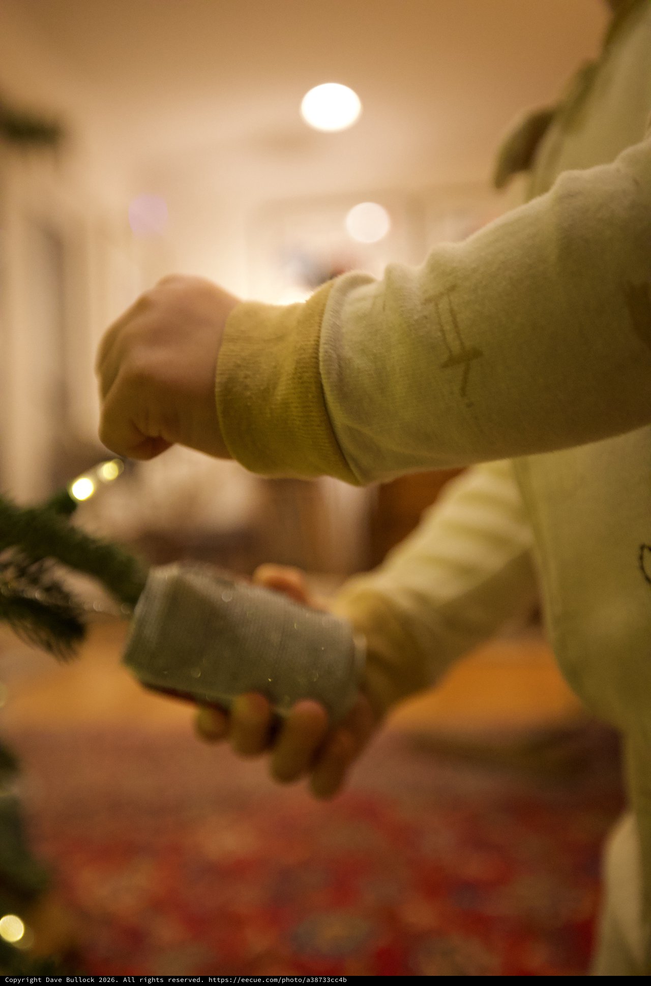 Hands Hanging Glass Ornament on Christmas Tree