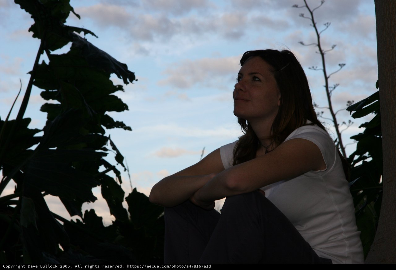 Woman Gazing Skyward at Twilight Among Tropical Foliage