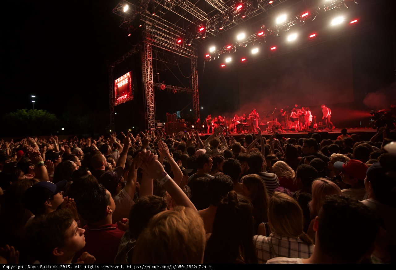 Belle and Sebastian Wide Stage Arms Raised Stadium Lights Red Haze Blonde Woman Crowd