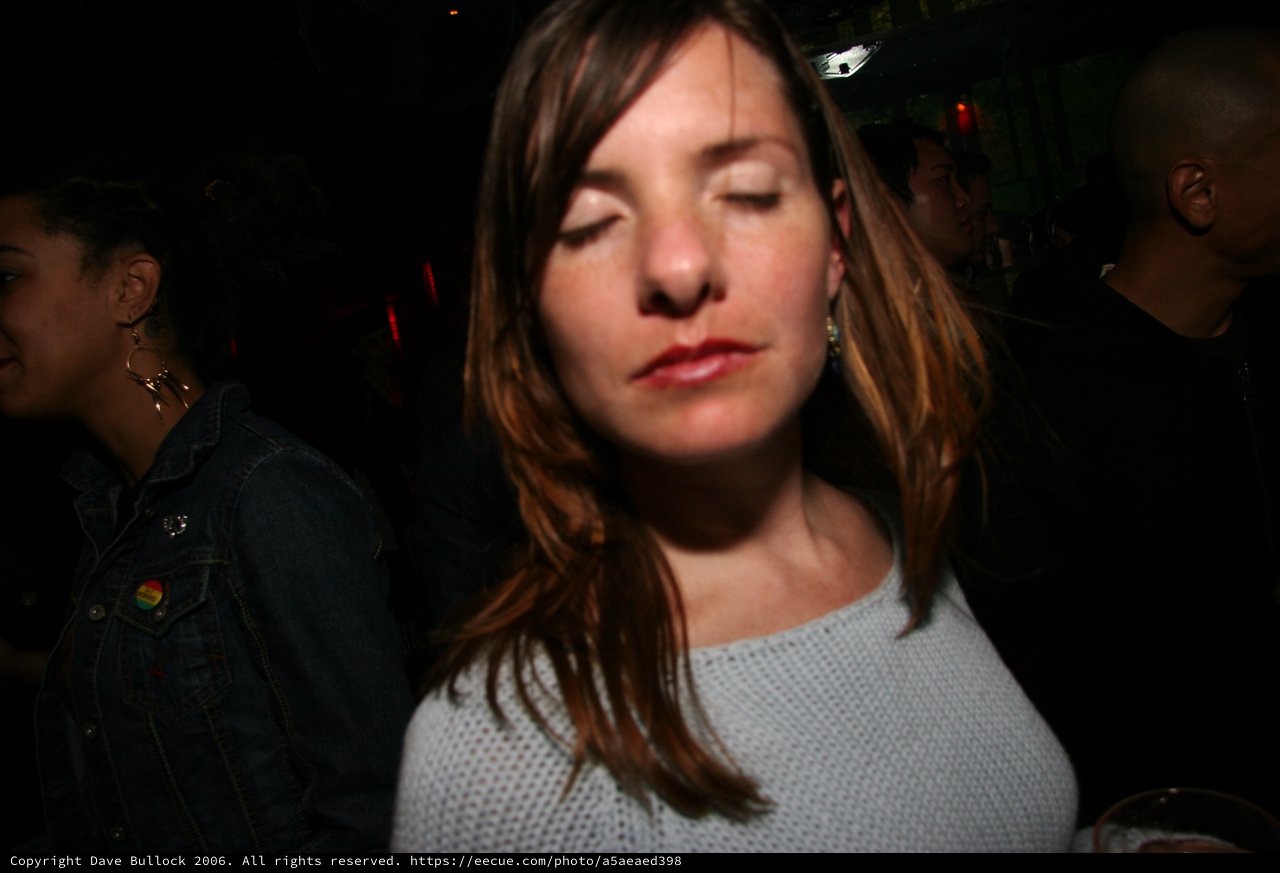 Woman Eyes Closed in Dimly Lit Nightclub