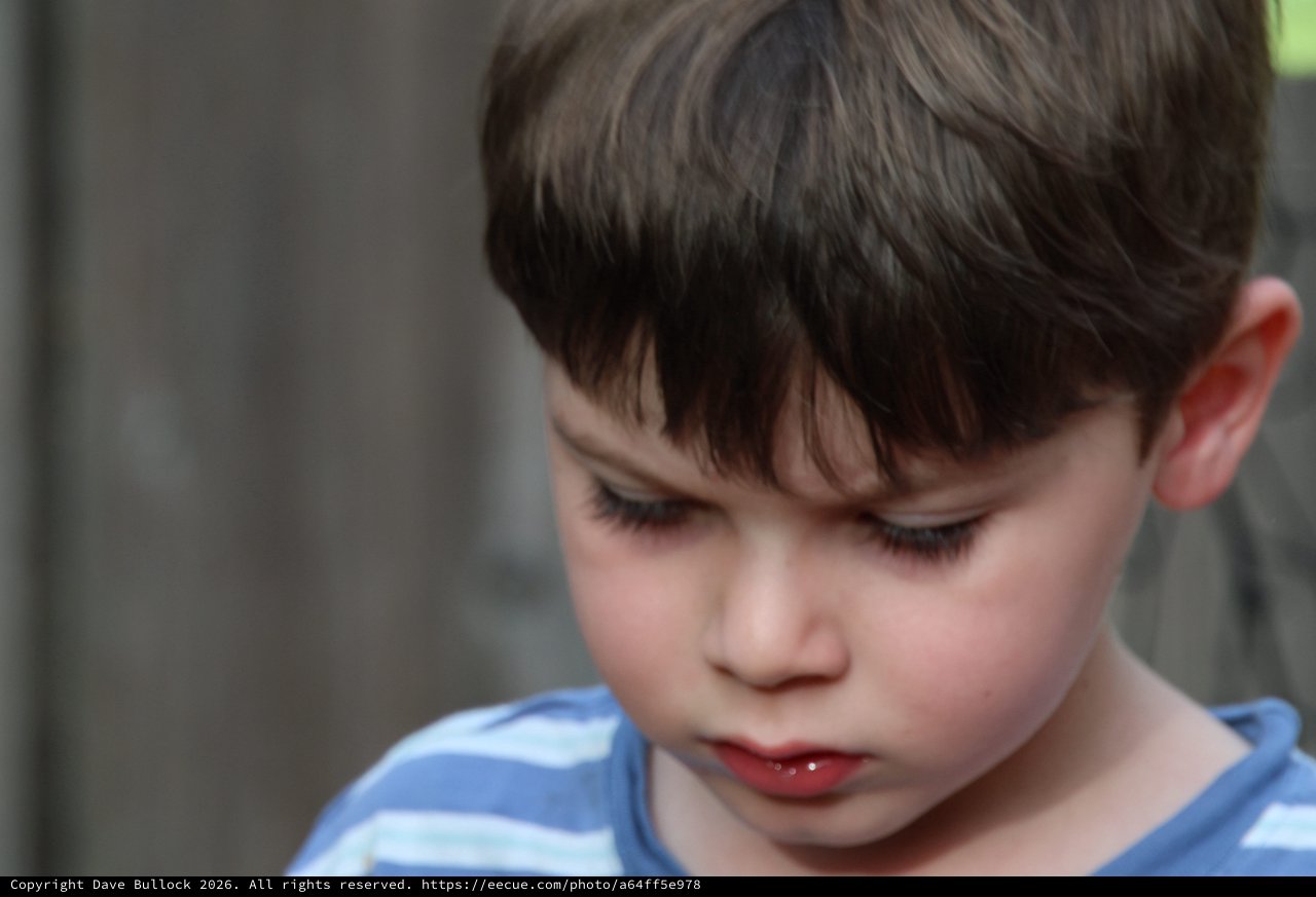 Young Child in Contemplative Moment, Blue Striped Shirt
